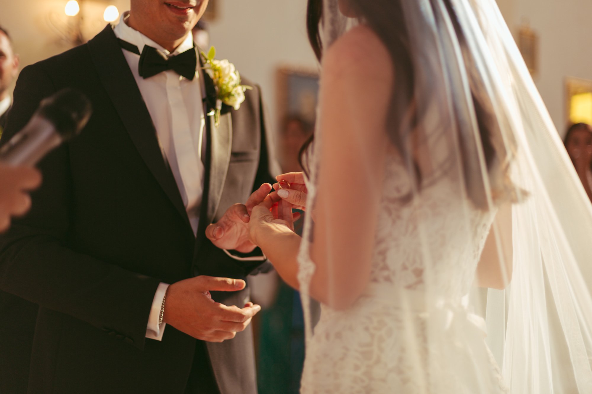 Primo piano del momento in cui la sposa infila l'anello nuziale al dito dello sposo durante la cerimonia