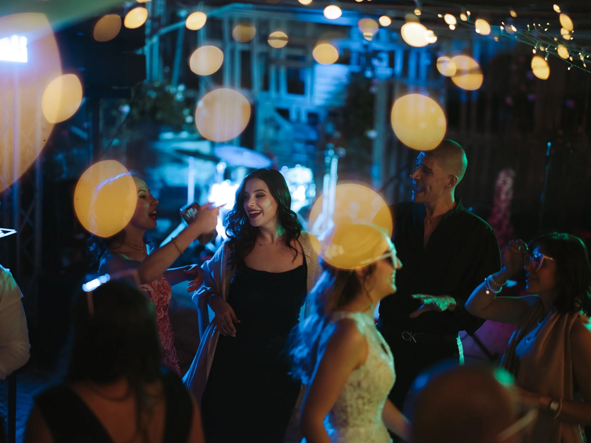 Invitati al matrimonio che ballano felici sulla pista sotto catene di luci dorate e soffuse