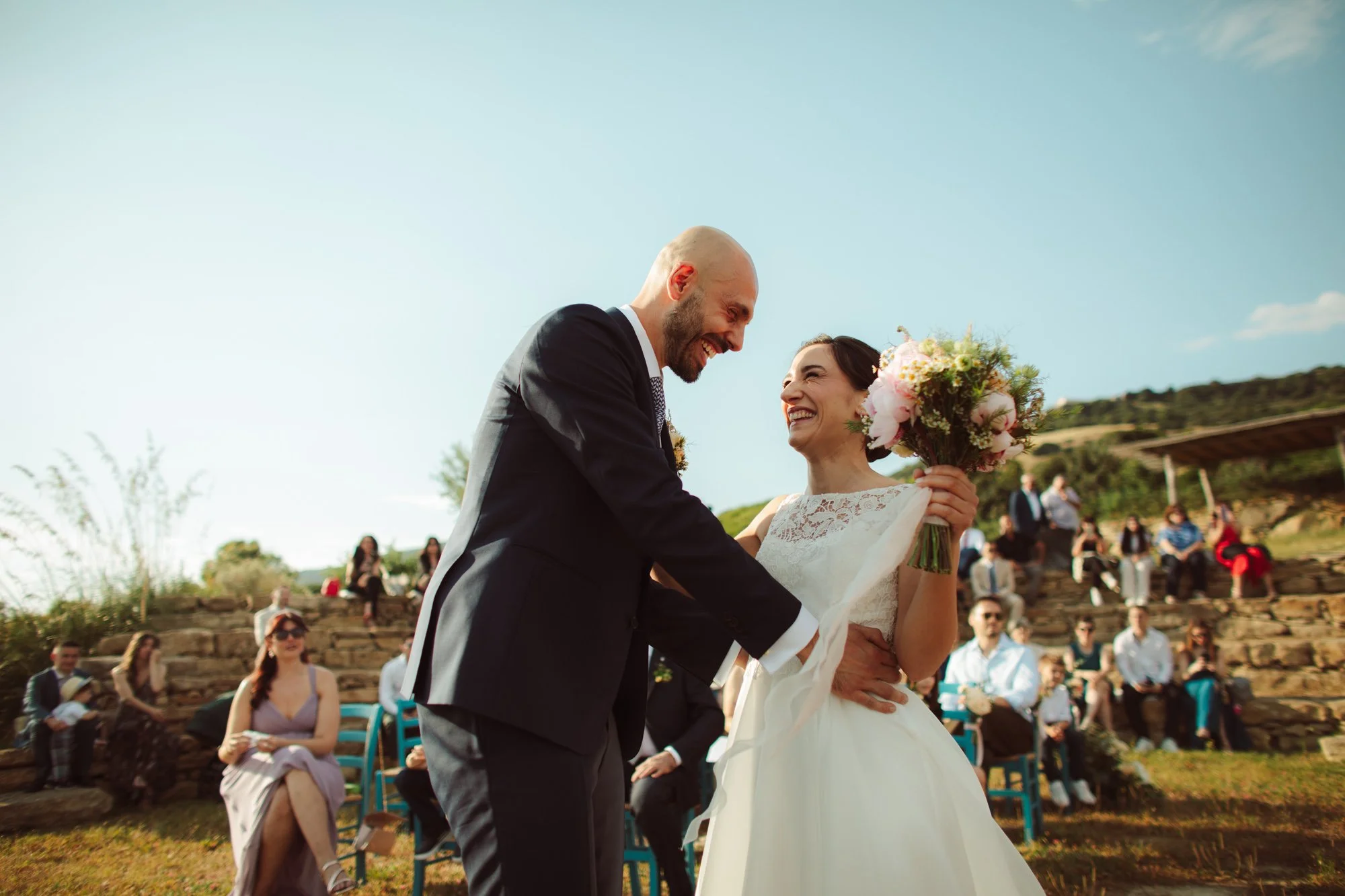 Sposi sorridenti e felici durante il rito del matrimonio all'aperto in Sardegna
