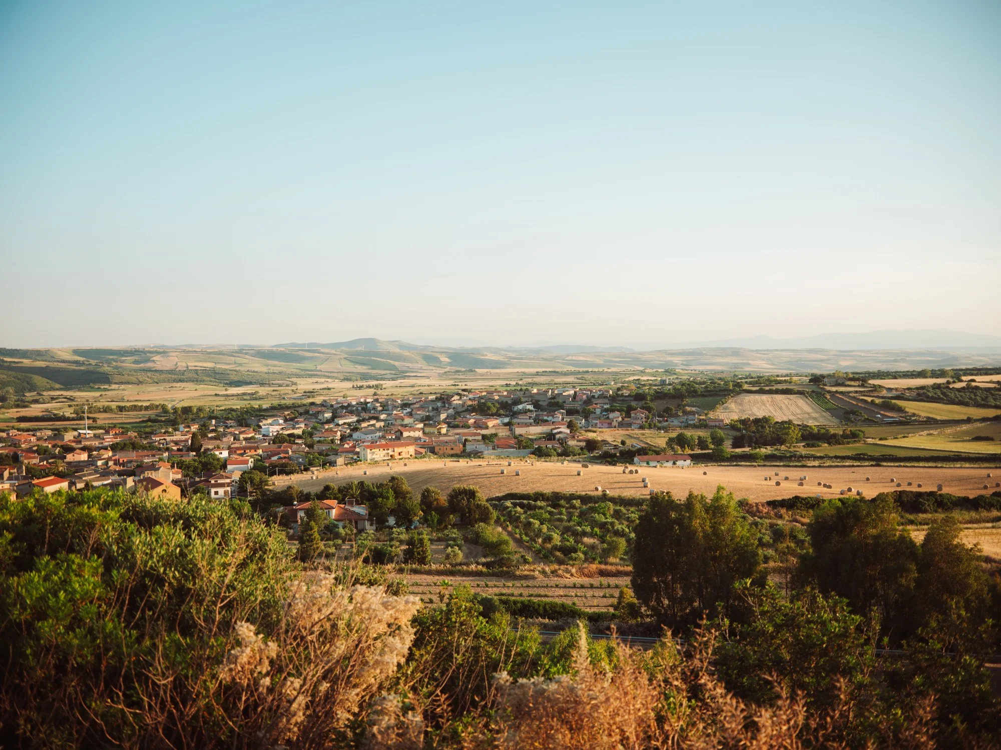 Vista panoramica dall'alto della campagna sarda e dei campi dorati al tramonto durante un matrimonio in Sardegna