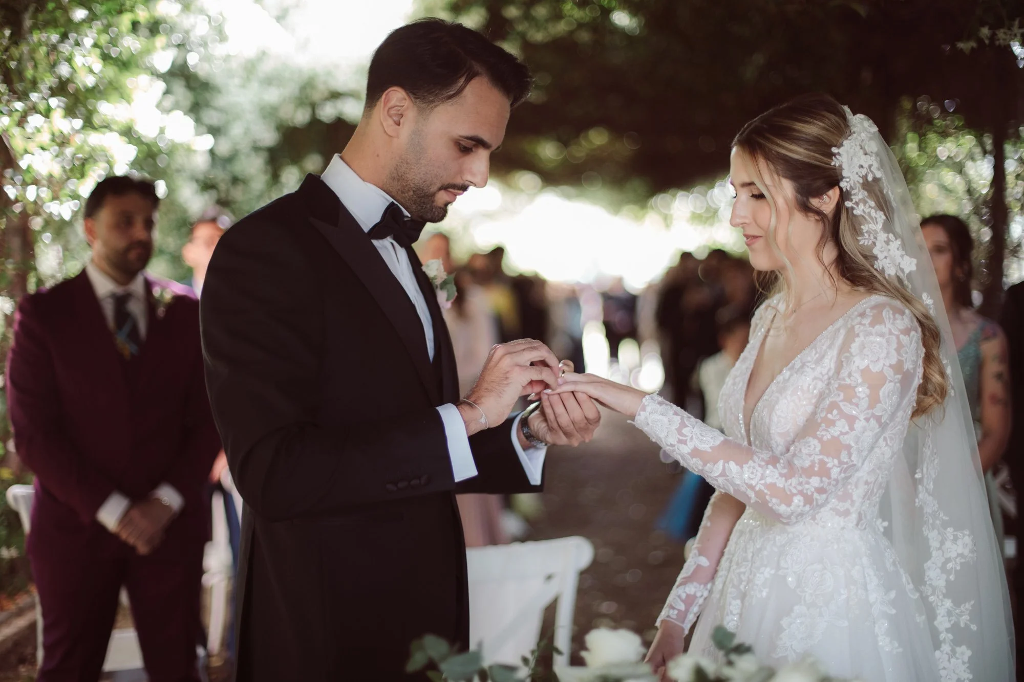 Lo sposo infila delicatamente la fede nuziale d'oro al dito della sposa durante lo scambio degli anelli