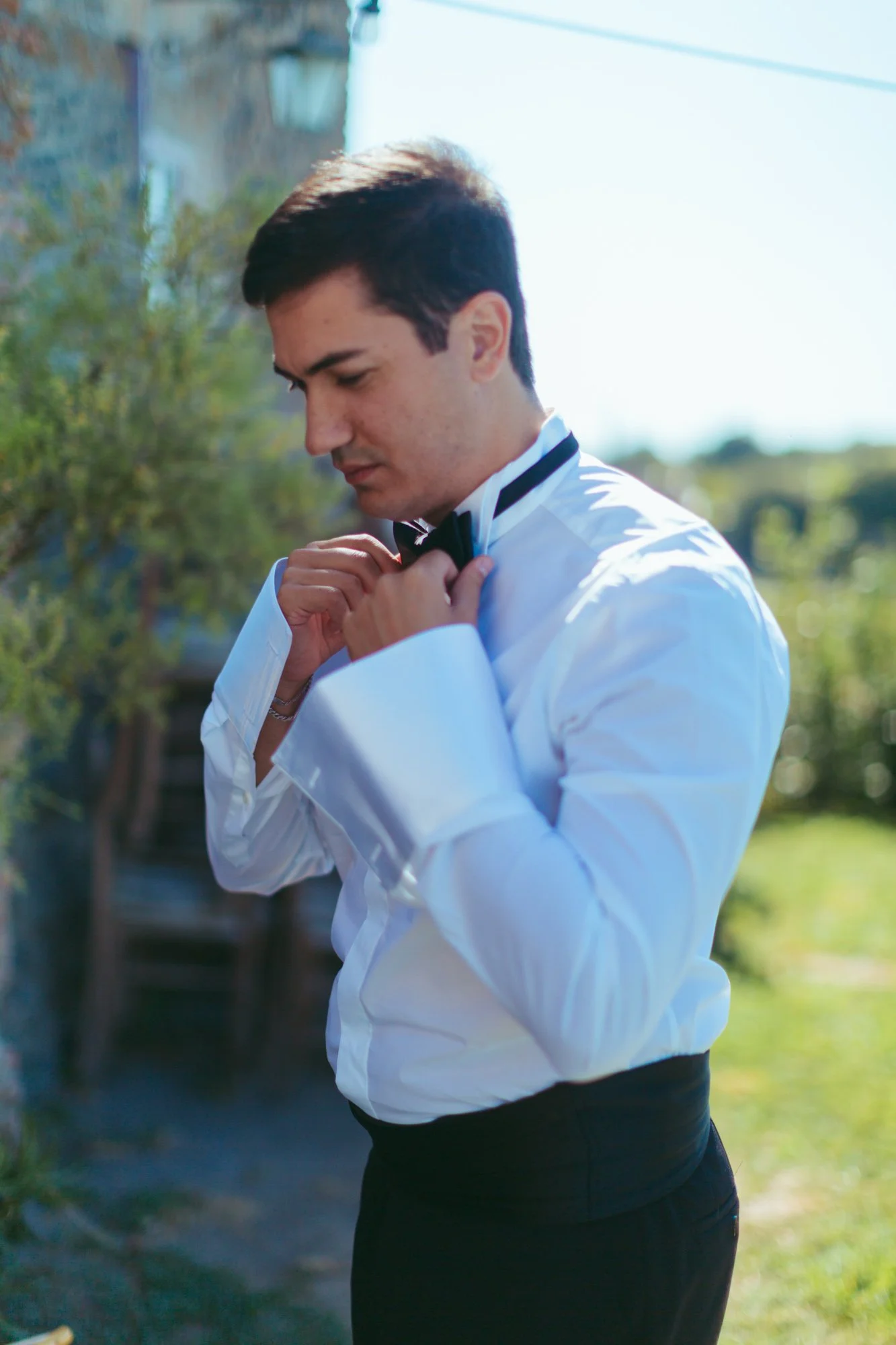 Ritratto dello sposo in camicia bianca e papillon nero nei giardini di Borgo di Tragliata