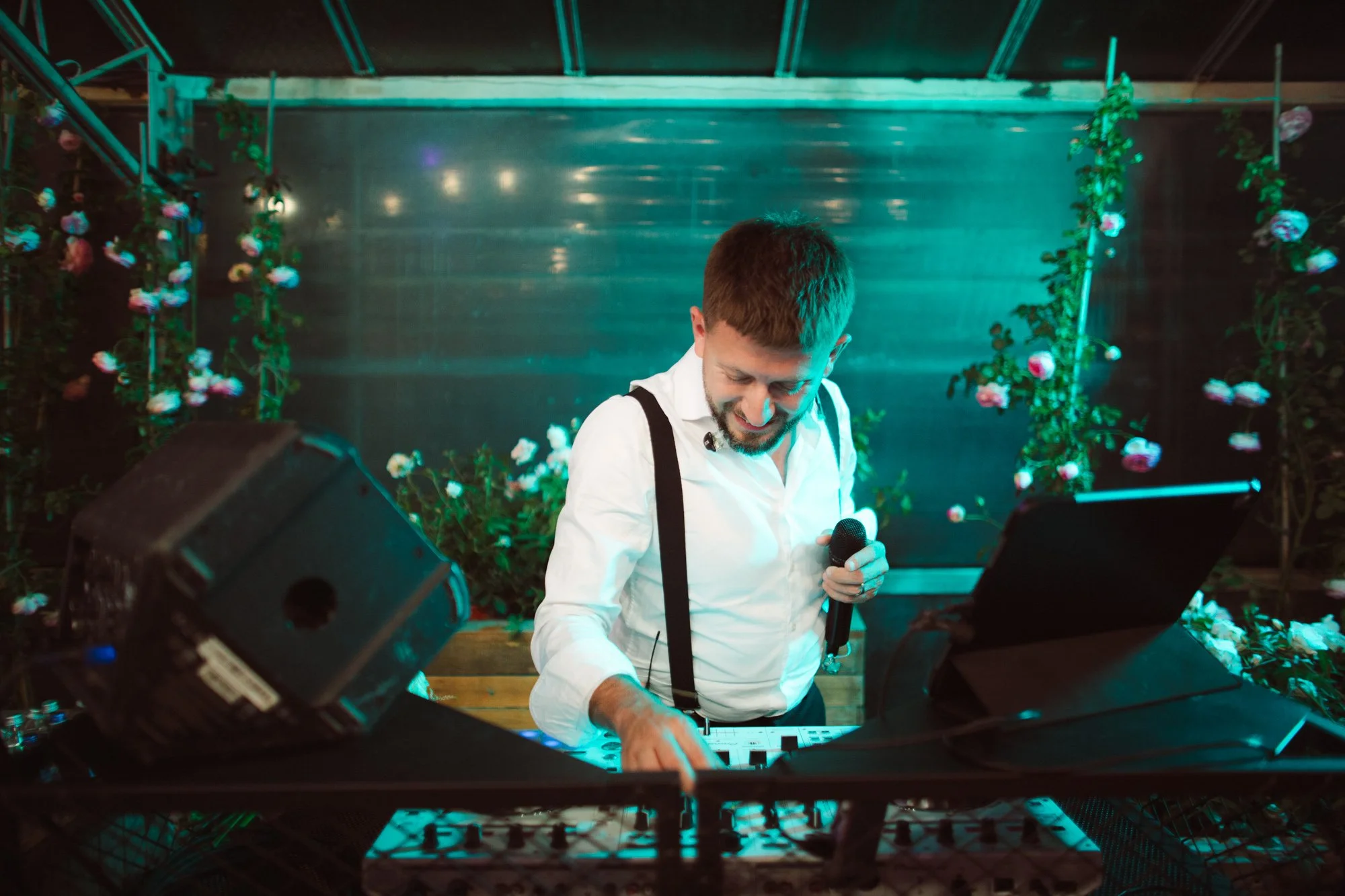 Il DJ alla consolle con microfono e tablet animatore della festa di matrimonio illuminata da luci verdi