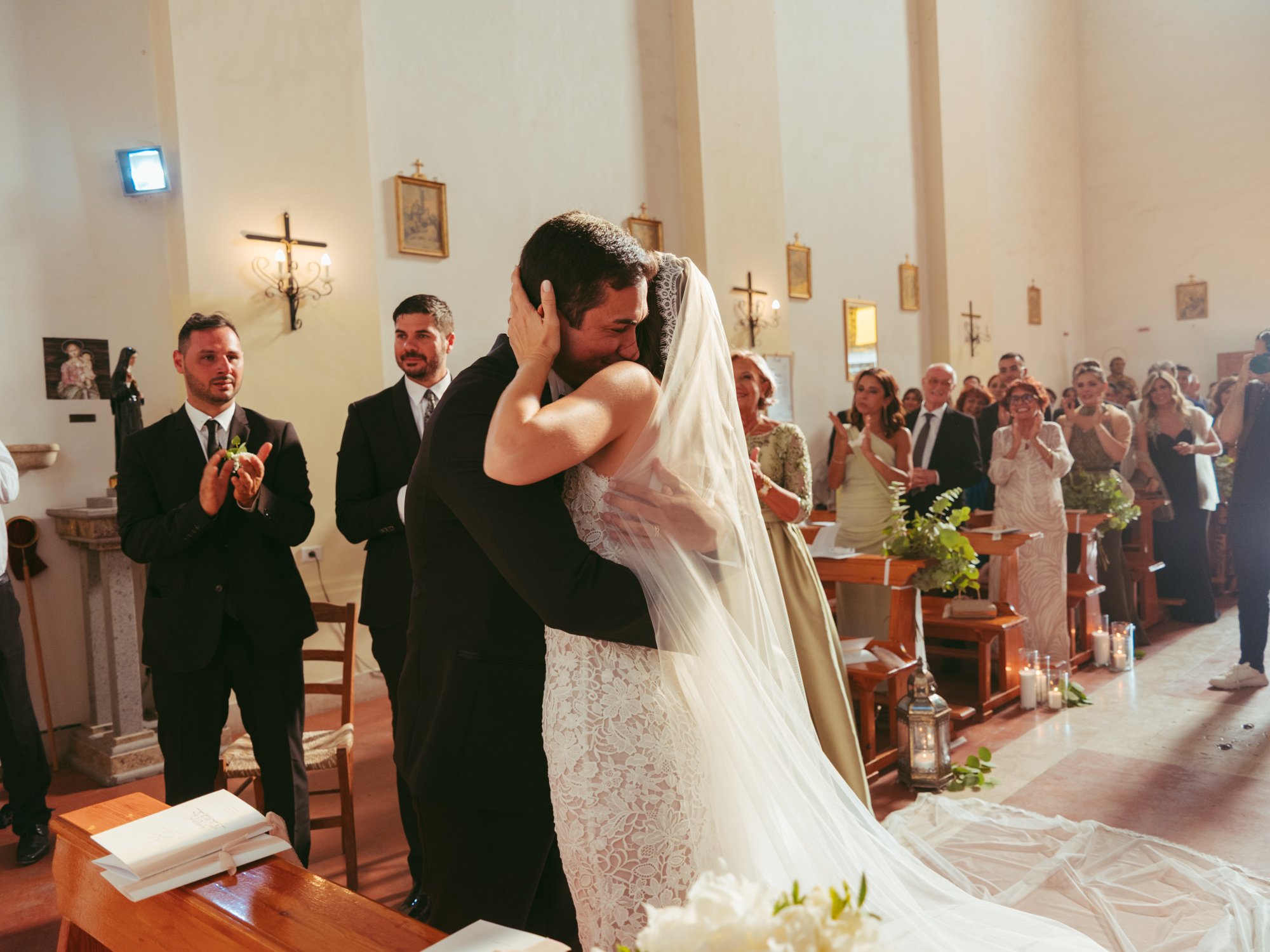 Lo sposo e la sposa si stringono in un abbraccio affettuoso all'altare tra gli applausi degli invitati