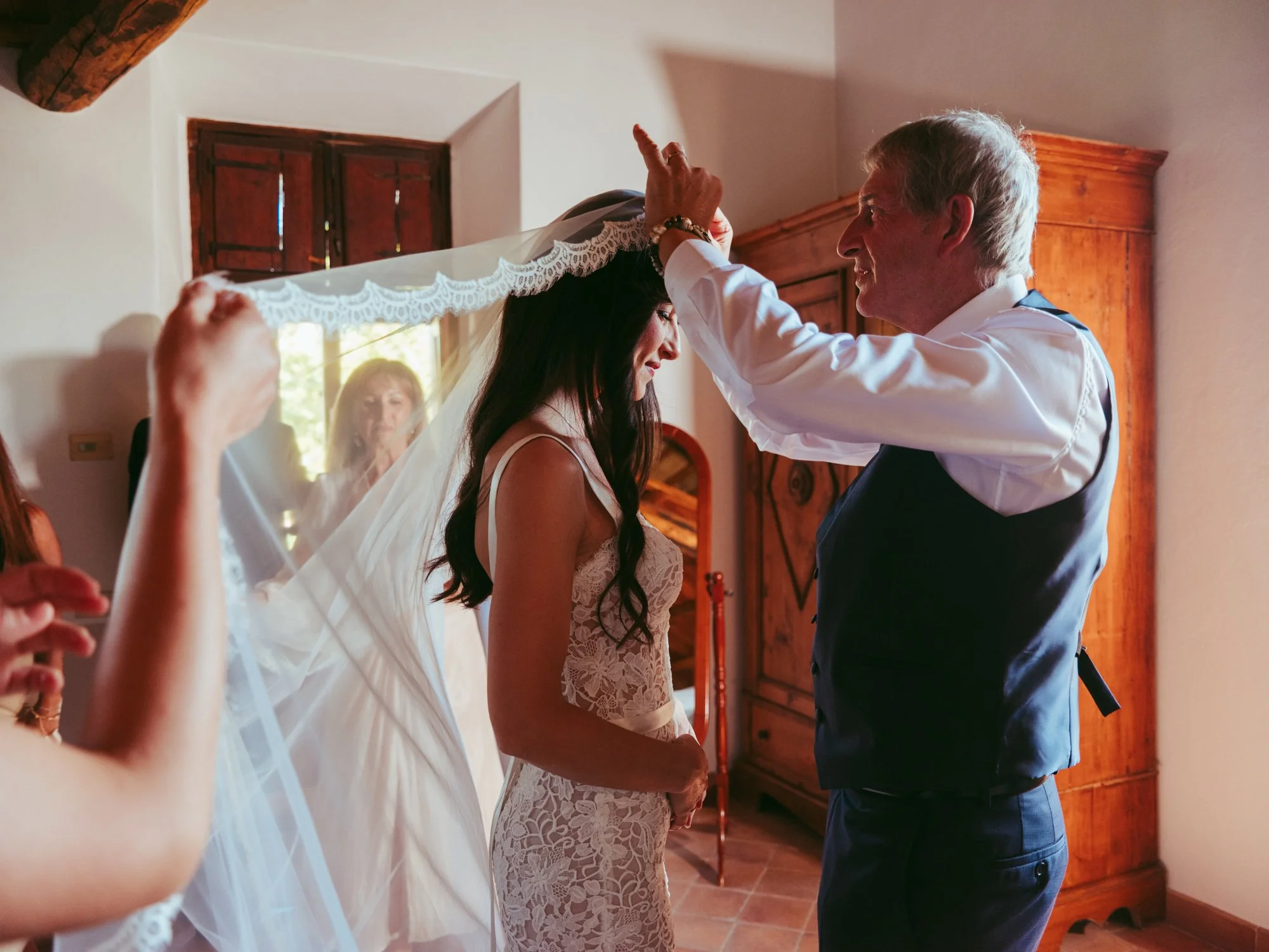 Il padre aggiusta delicatamente il velo in pizzo sulla testa della sposa