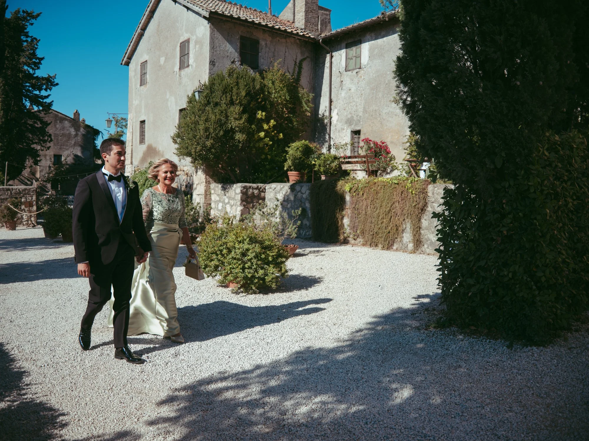 Lo sposo cammina mano nella mano con la madre vestita con un elegante abito verde per raggiungere la cerimonia