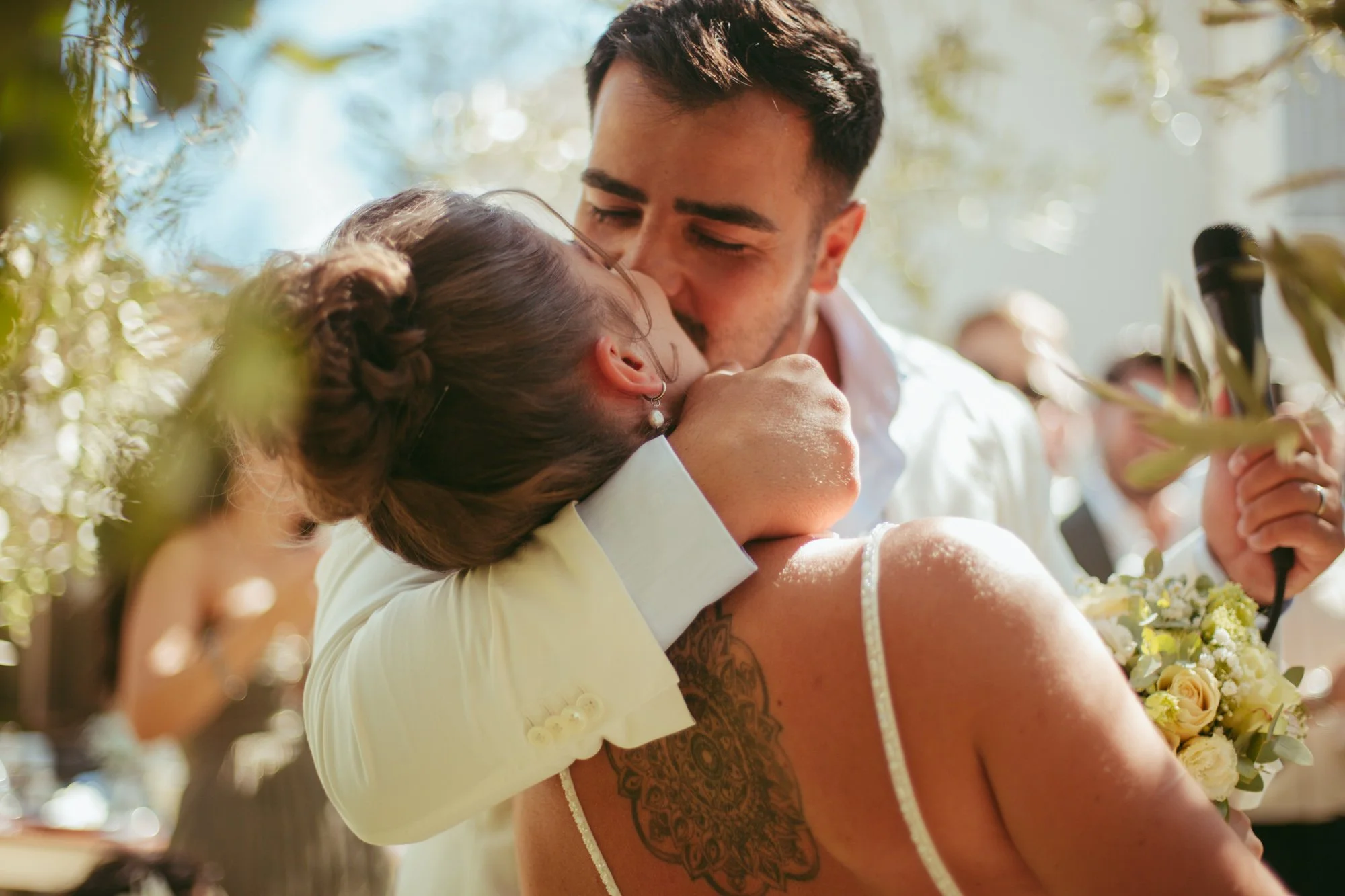 Primo piano del bacio romantico tra gli sposi al termine della cerimonia tra le fronde degli ulivi