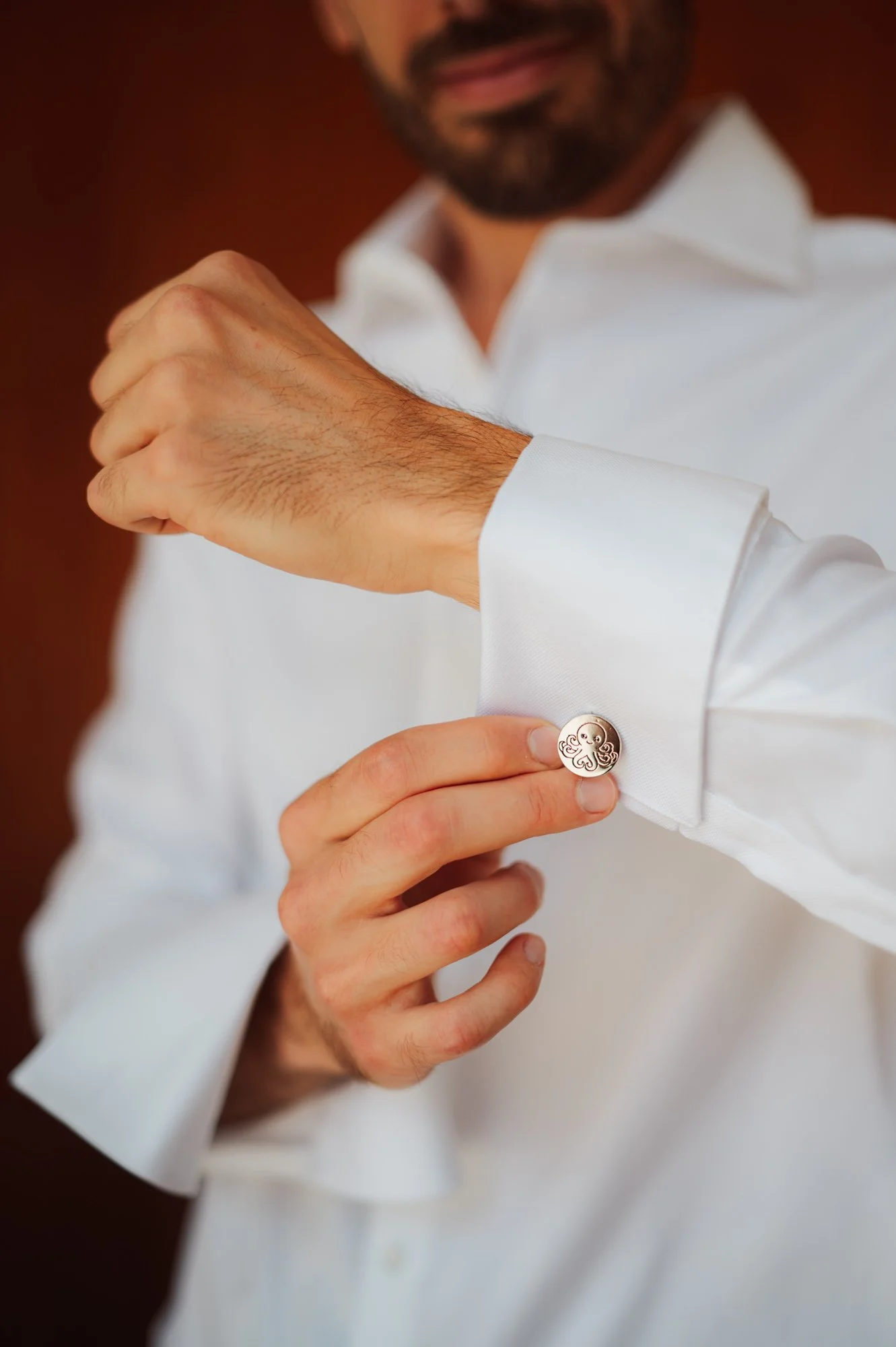 Primo piano dei gemelli della camicia dello sposo durante la vestizione