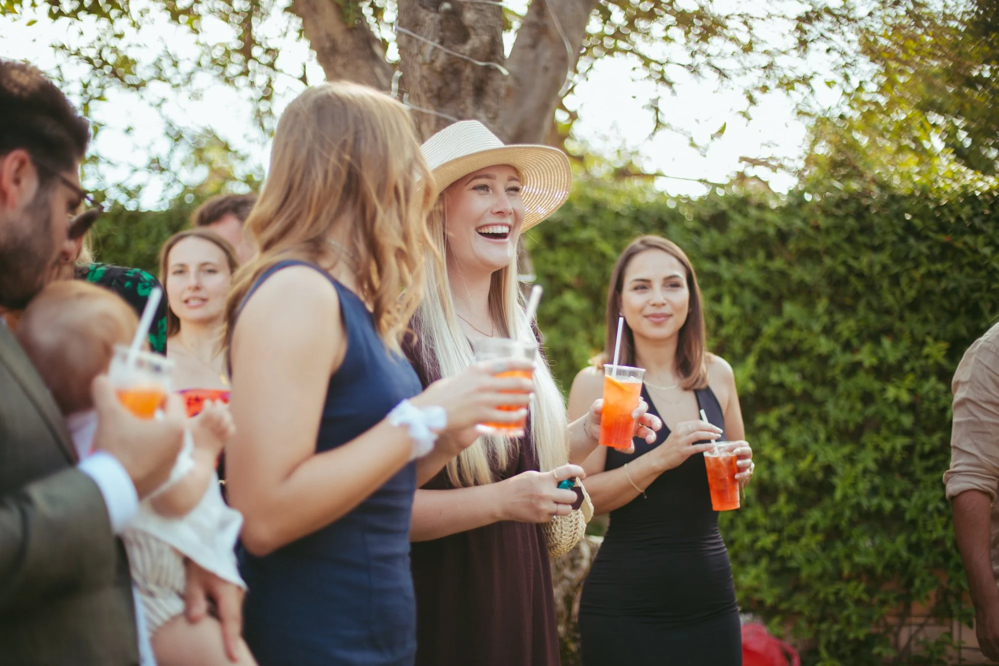 Gruppo di invitate sorridenti che brindano con cocktail Spritz durante l'aperitivo di nozze in giardino