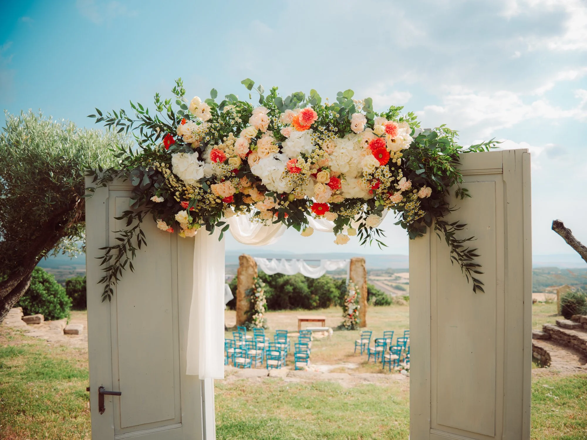 Porta in legno decorata con fiori per l'ingresso alla cerimonia di matrimonio all'aperto