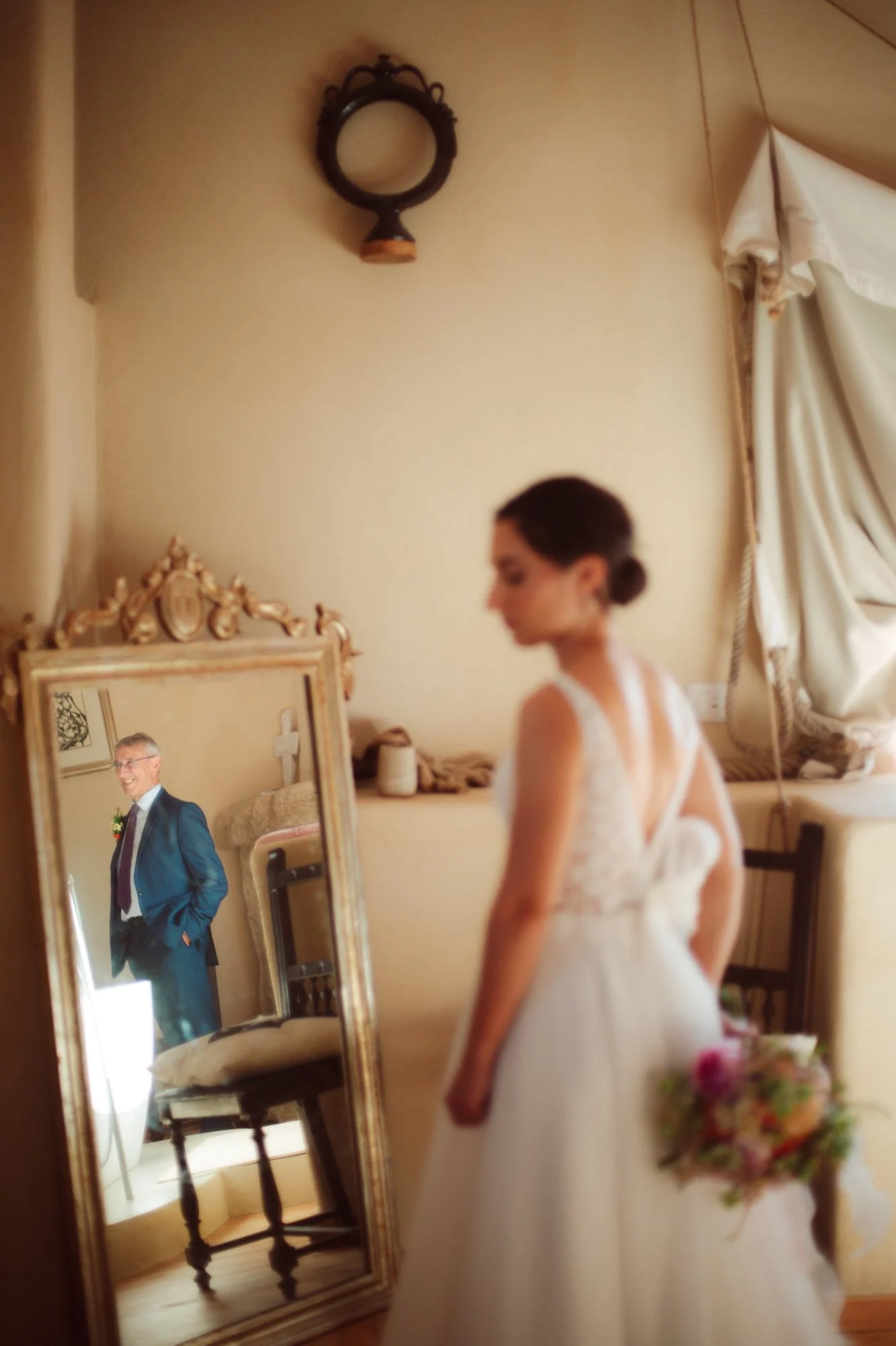 Il padre della sposa riflesso in uno specchio dorato mentre osserva la figlia durante i preparativi