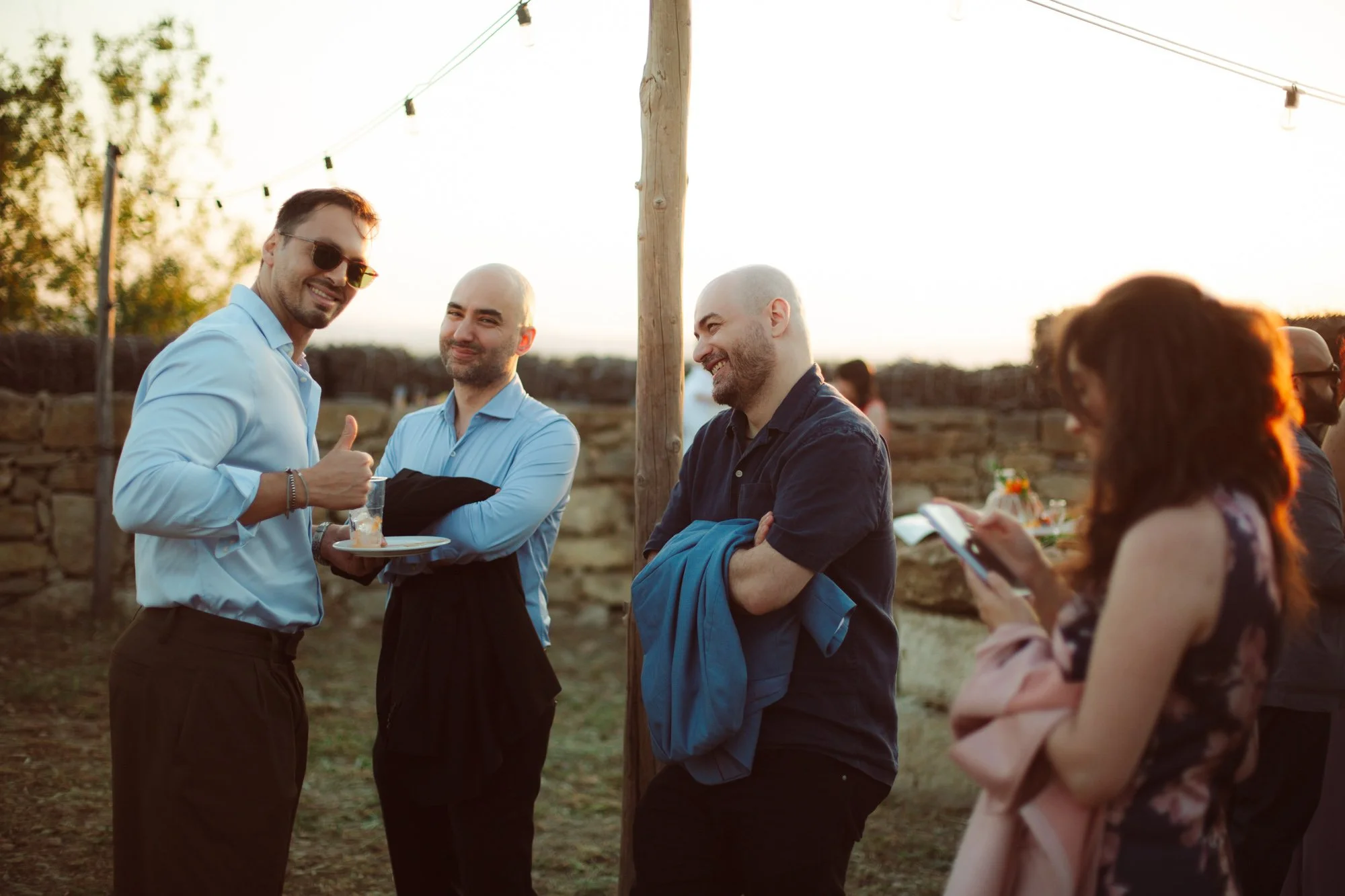 Invitati al matrimonio che chiacchierano durante l'aperitivo all'aperto in Sardegna al tramonto