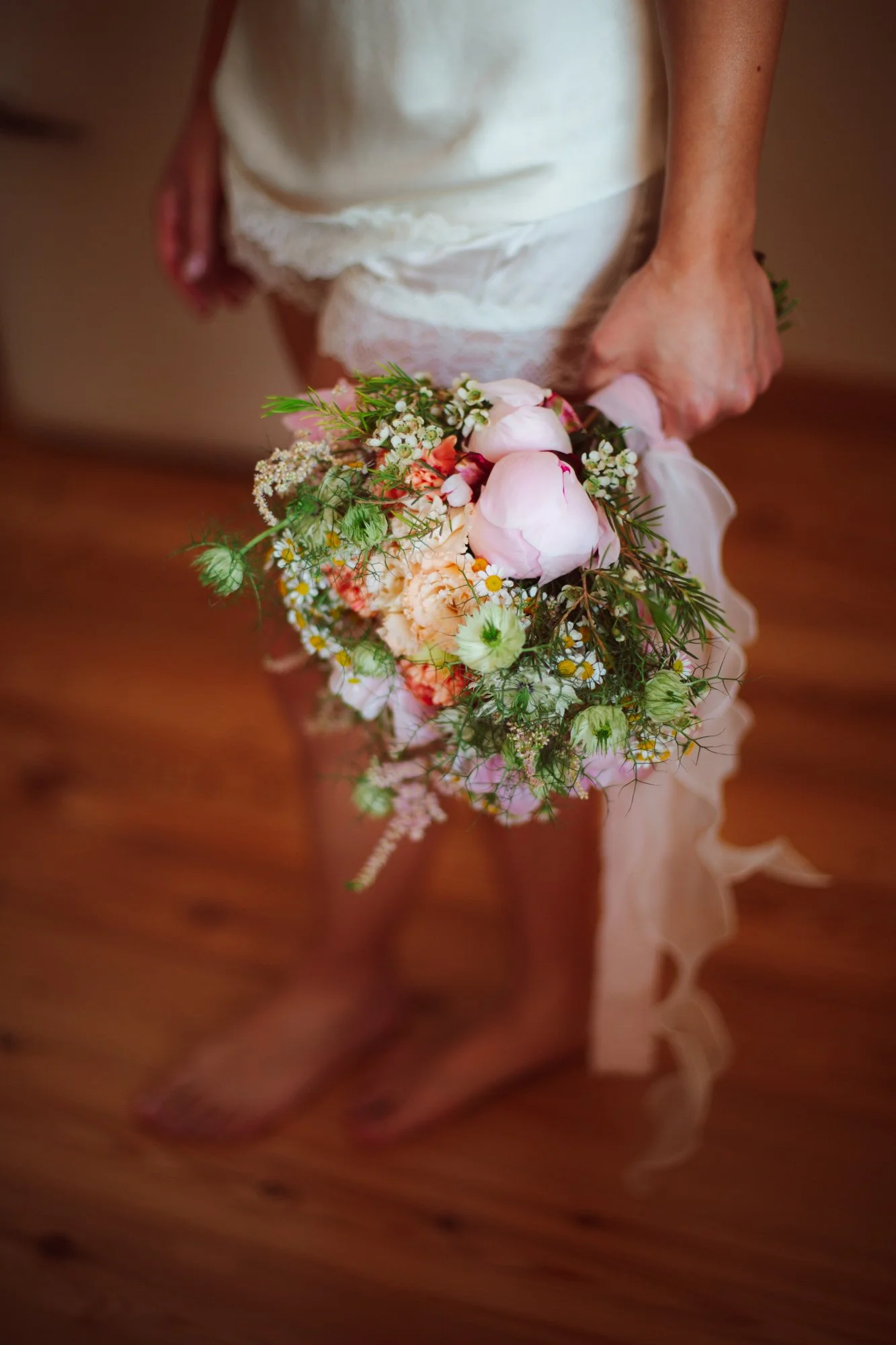 Dettaglio del bouquet della sposa con peonie rosa e fiori di campo durante la preparazione del matrimonio in Sardegna