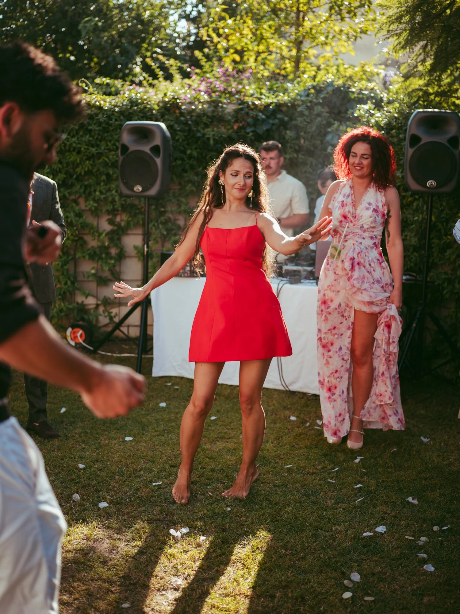 Invitata in abito rosso corto balla a piedi nudi sull'erba di fronte al DJ della festa di nozze"