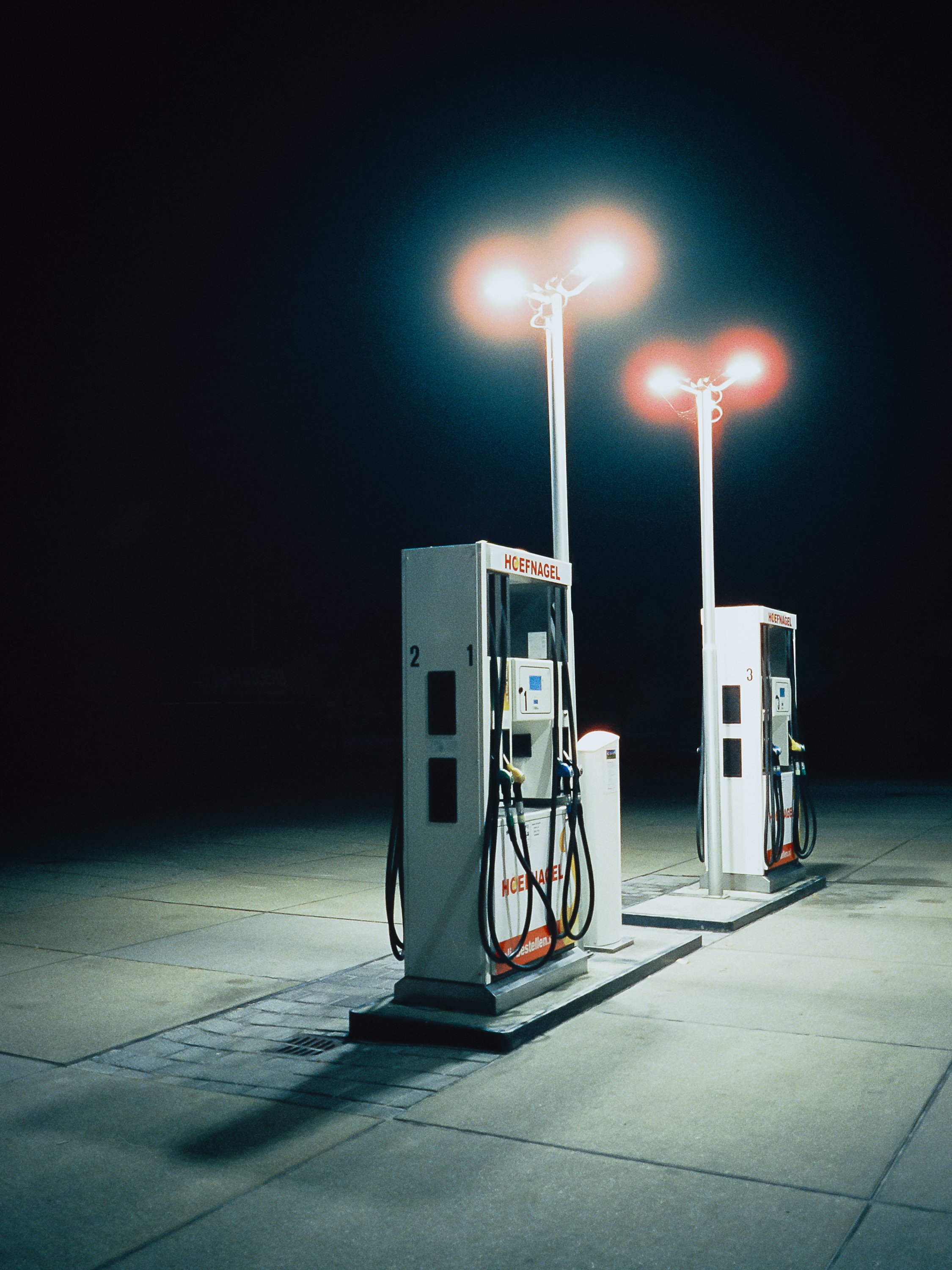 Nighttime scene of multiple electric vehicle charging stations with illuminated streetlights in the background.
