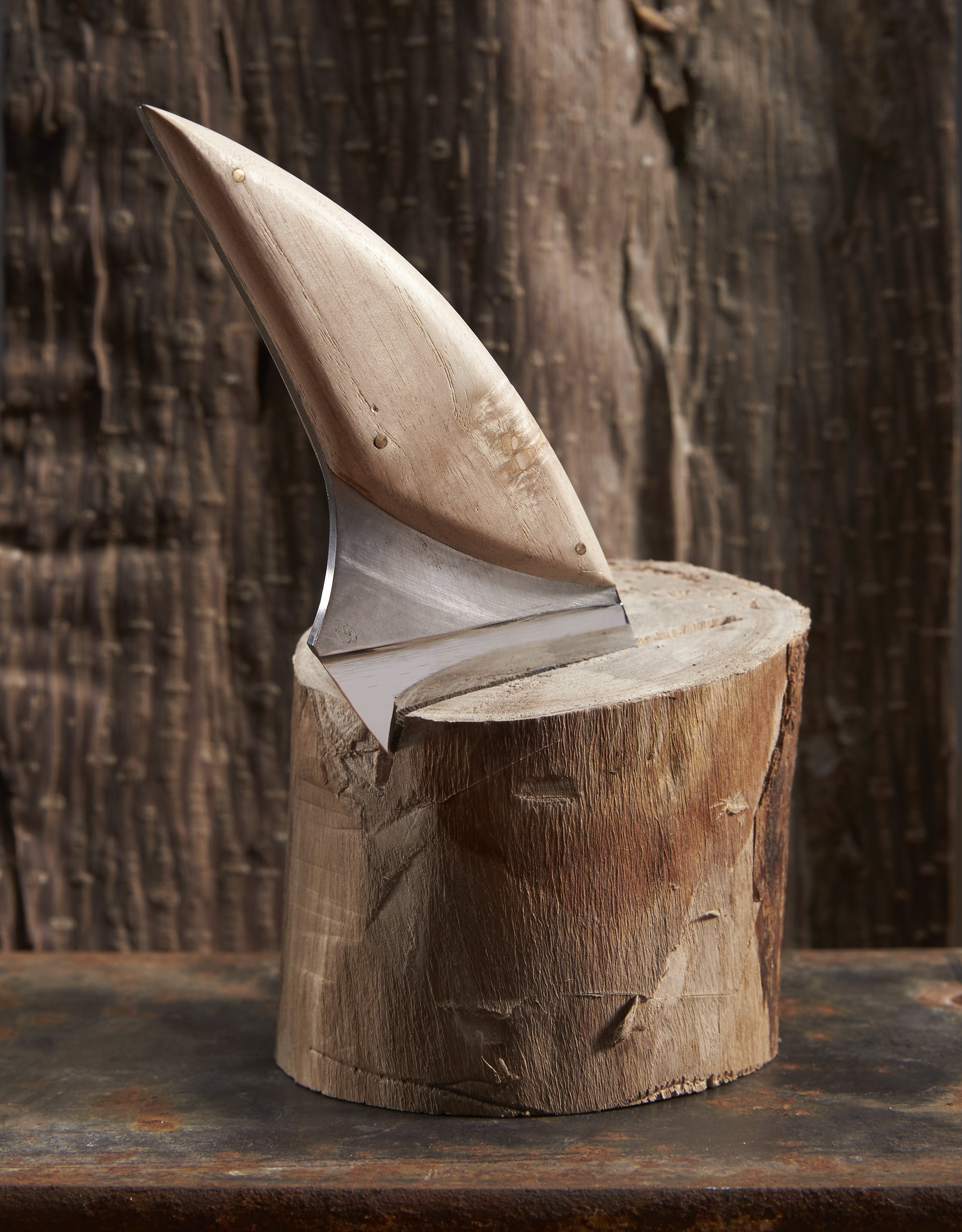 Un couteau de chef le Puck avec une lame en acier et une poignée en bois de paulownia est placé sur un socle en bois, avec un fond en bois rustique.