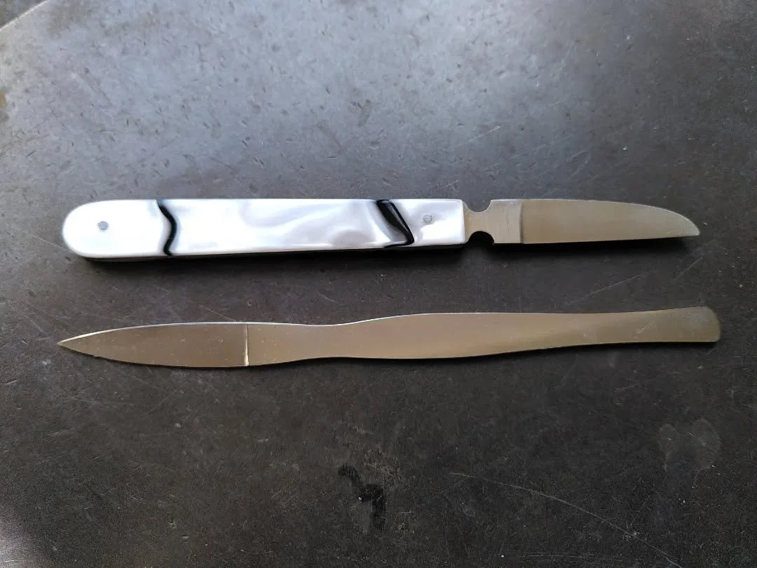 Deux couteaux de métier pour plumassier, l'un avec un manche en résine effet nacre.