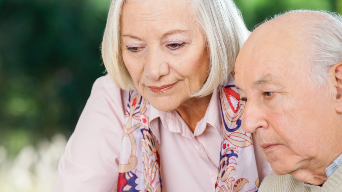 A worried older man is helped by a woman with grey hair.