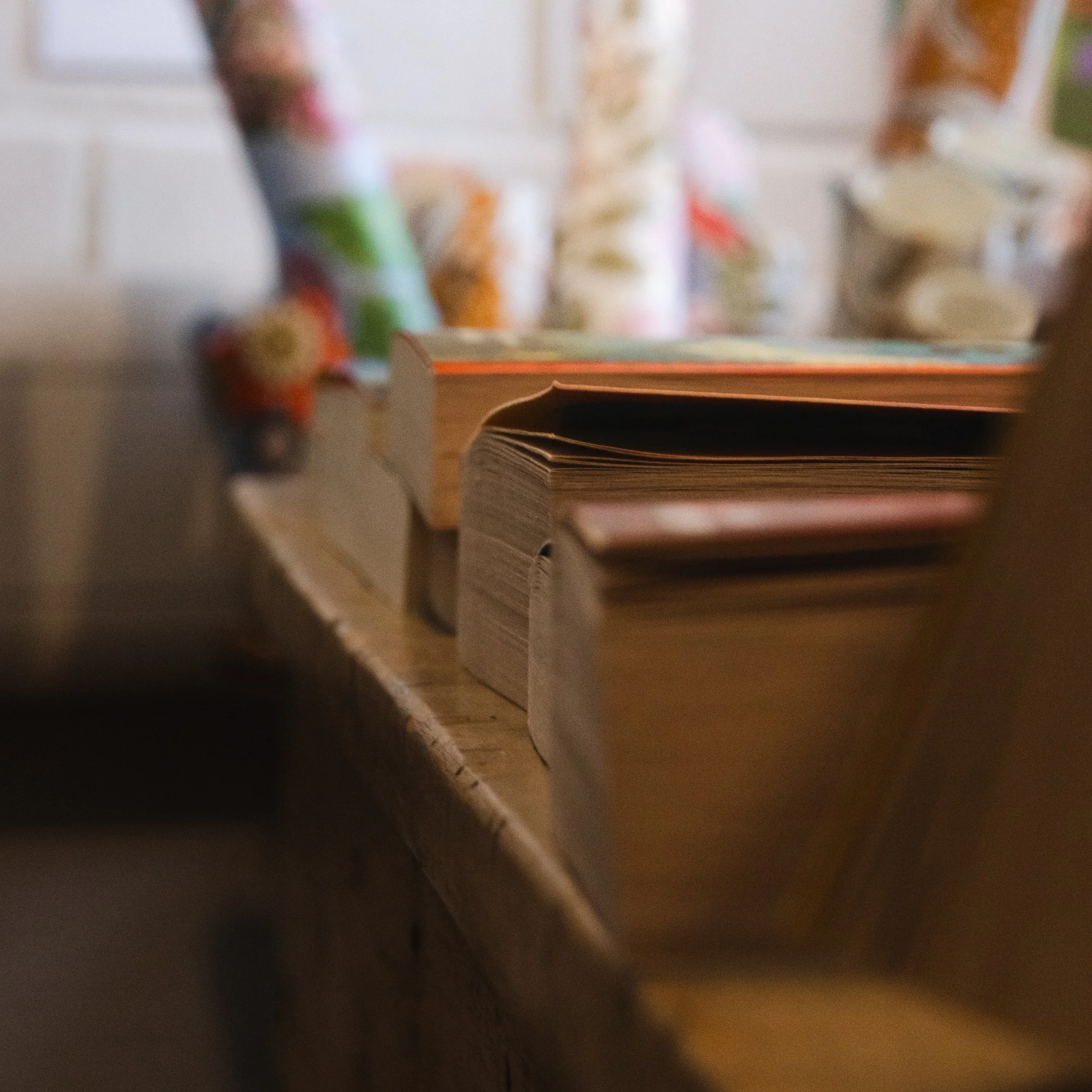 Blurred image of stacked colorful books on a table, with a book in the foreground.