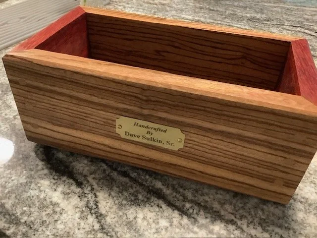 A rectangular wooden box with a brass nameplate inside that reads 'Handcrafted by Dave Sulkid, S.F.'