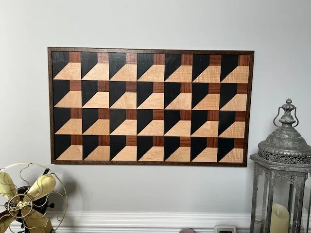 Wooden geometric wall art with squares and triangles in black, natural wood, and dark brown tones.