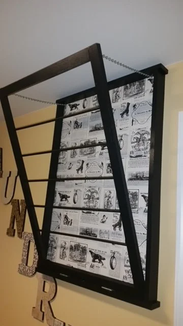 Black window frame filled with black-and-white comic strips hung on a beige wall.