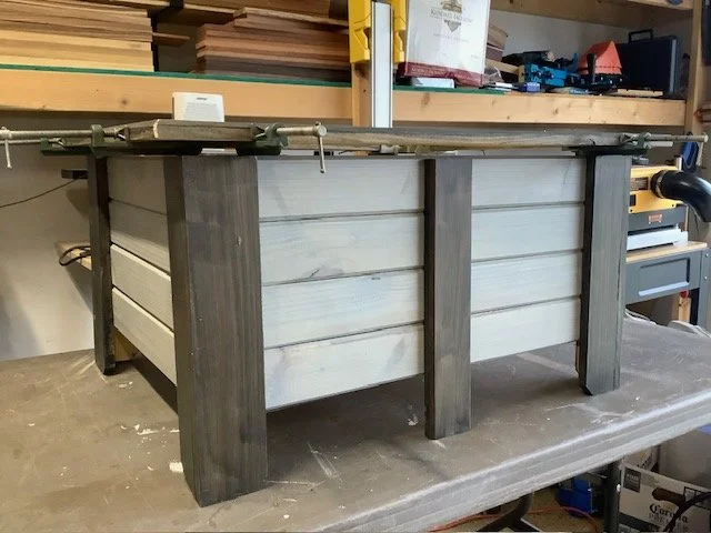 Wooden planter box under construction with vertical support beams, in a workshop.