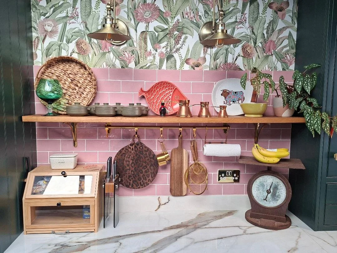 Kitchen worktop prep area with shelf styled in front of pink metro tiles and botanical print wallpaper