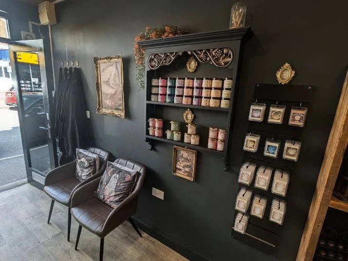 Hair salon waiting area with seating and a retail display showcasing wax melts and other products