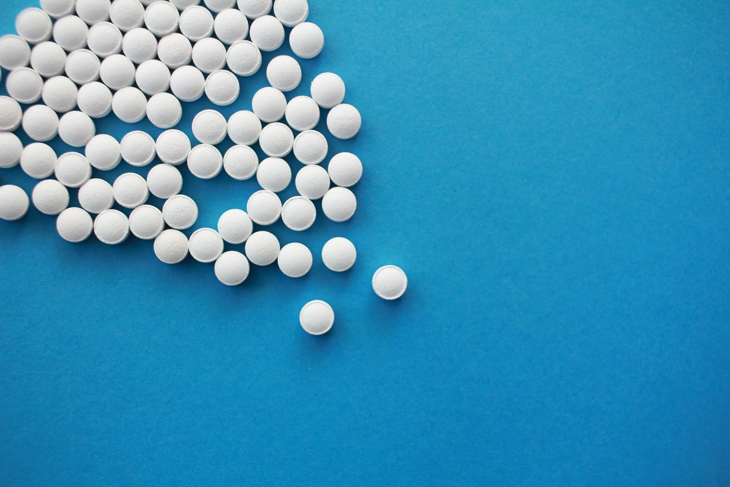 Scattered white pills on a blue background.