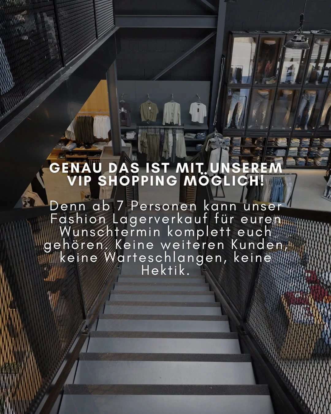Blick auf eine Treppe in einem Modegeschäft mit Sicht auf die obere Verkaufsebene, auf der Kleidung in Regalen und an der Wand präsentiert wird.