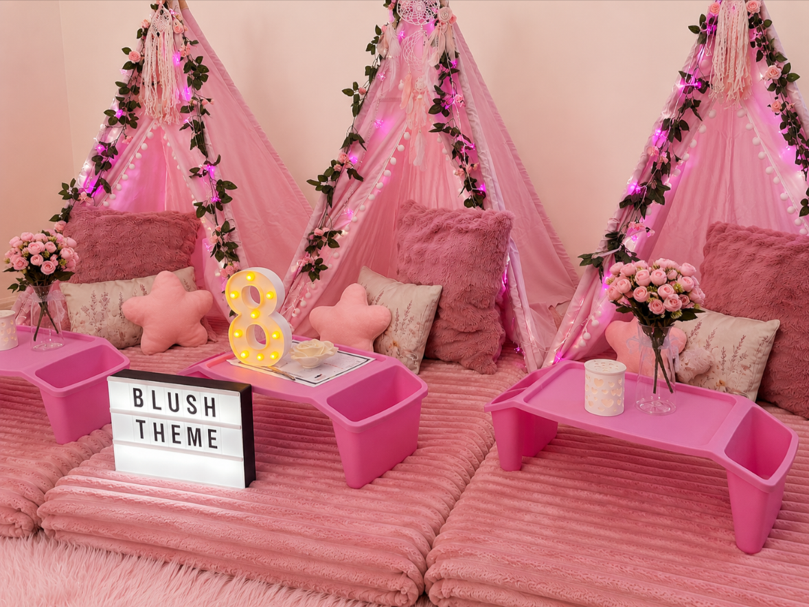 Pink teepee slumber party set-up with fluffy cushions, blankets and rugs. Decorative balloons and flowers.  Sign saying "Blush Theme".  Teepee slumber parties Geelong.