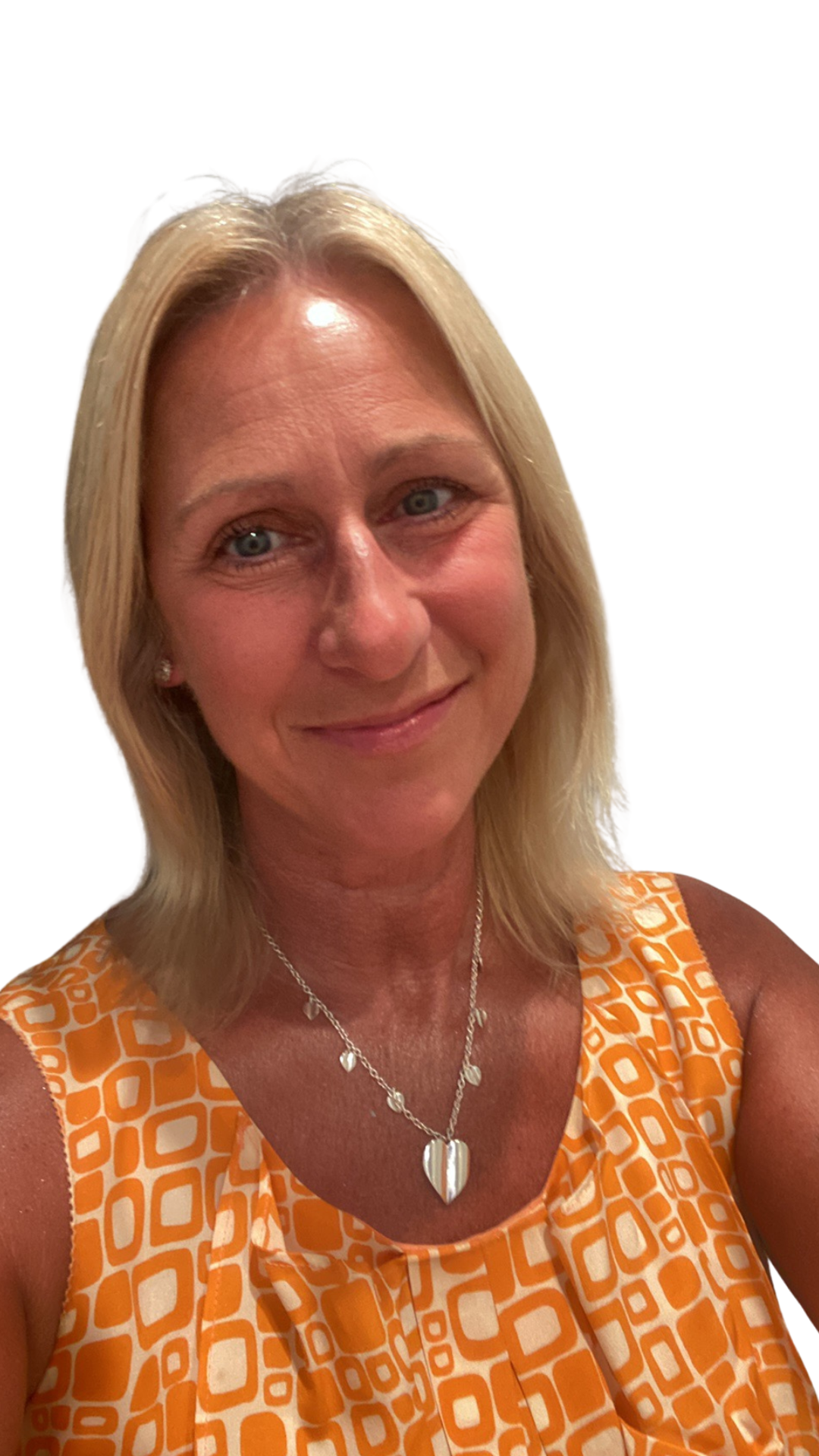 Close-up of a woman with blonde hair, wearing a sleeveless orange patterned dress and a silver necklace with a heart-shaped pendant, smiling.