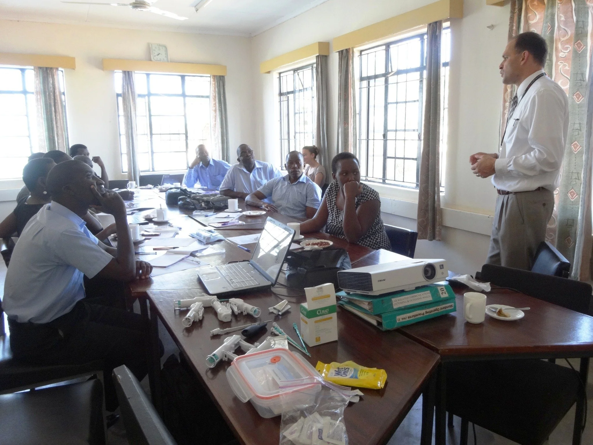 A group of doctors attending a medical training session in a room with large windows