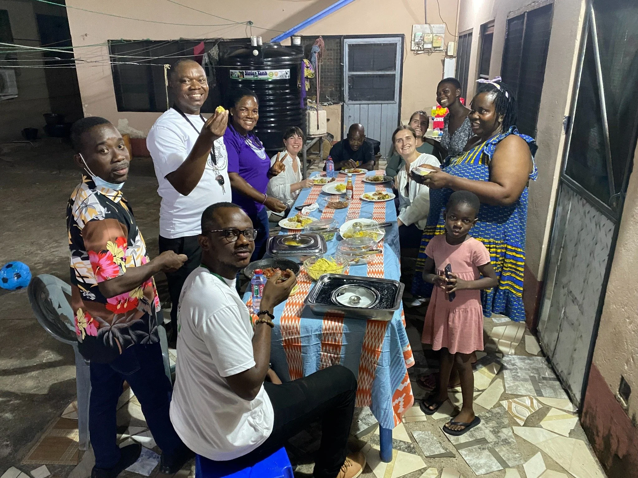 A group of people gathered around a dinner table outdoors at night