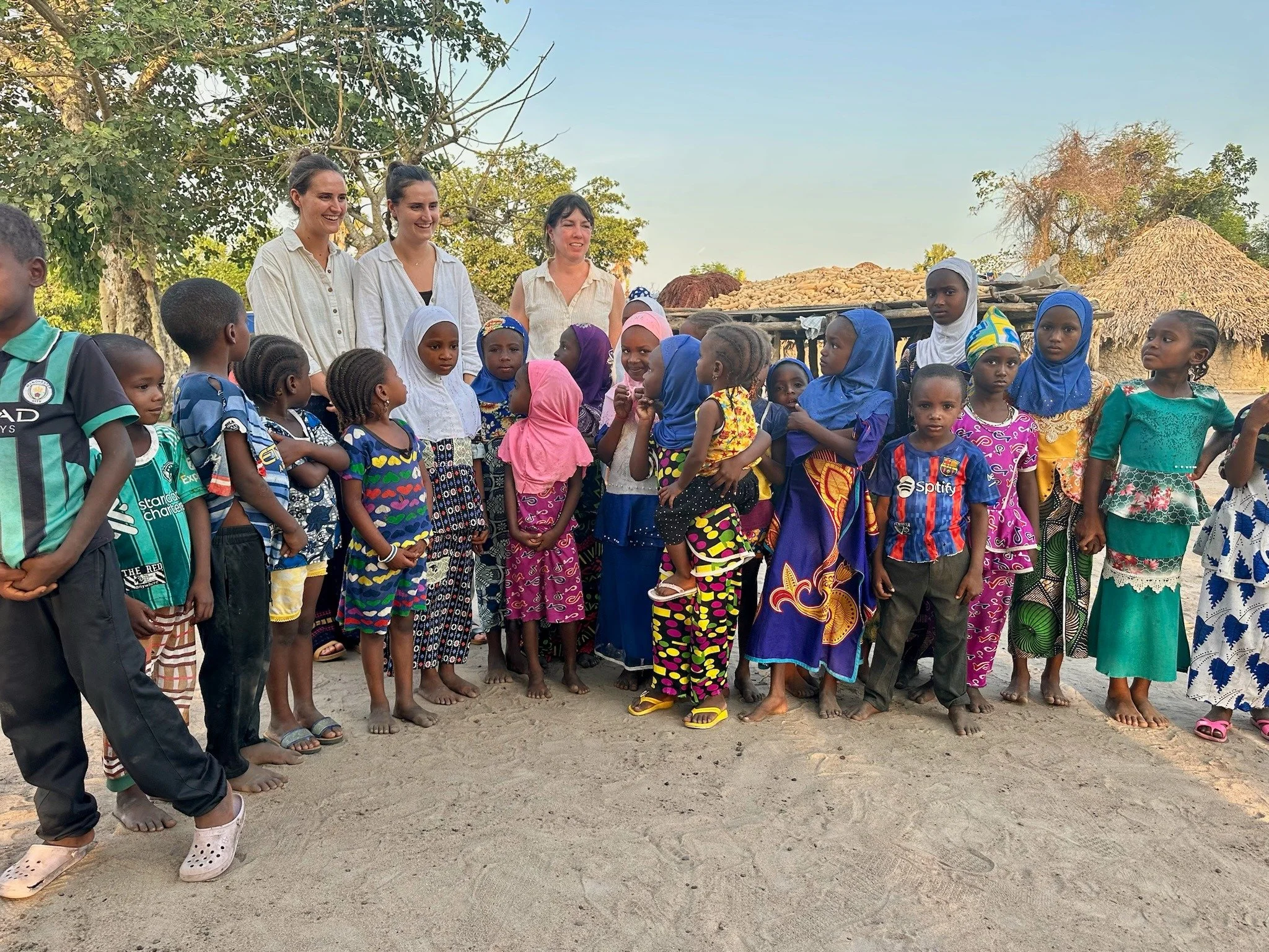 Women and children gather outdoors in a rural area 