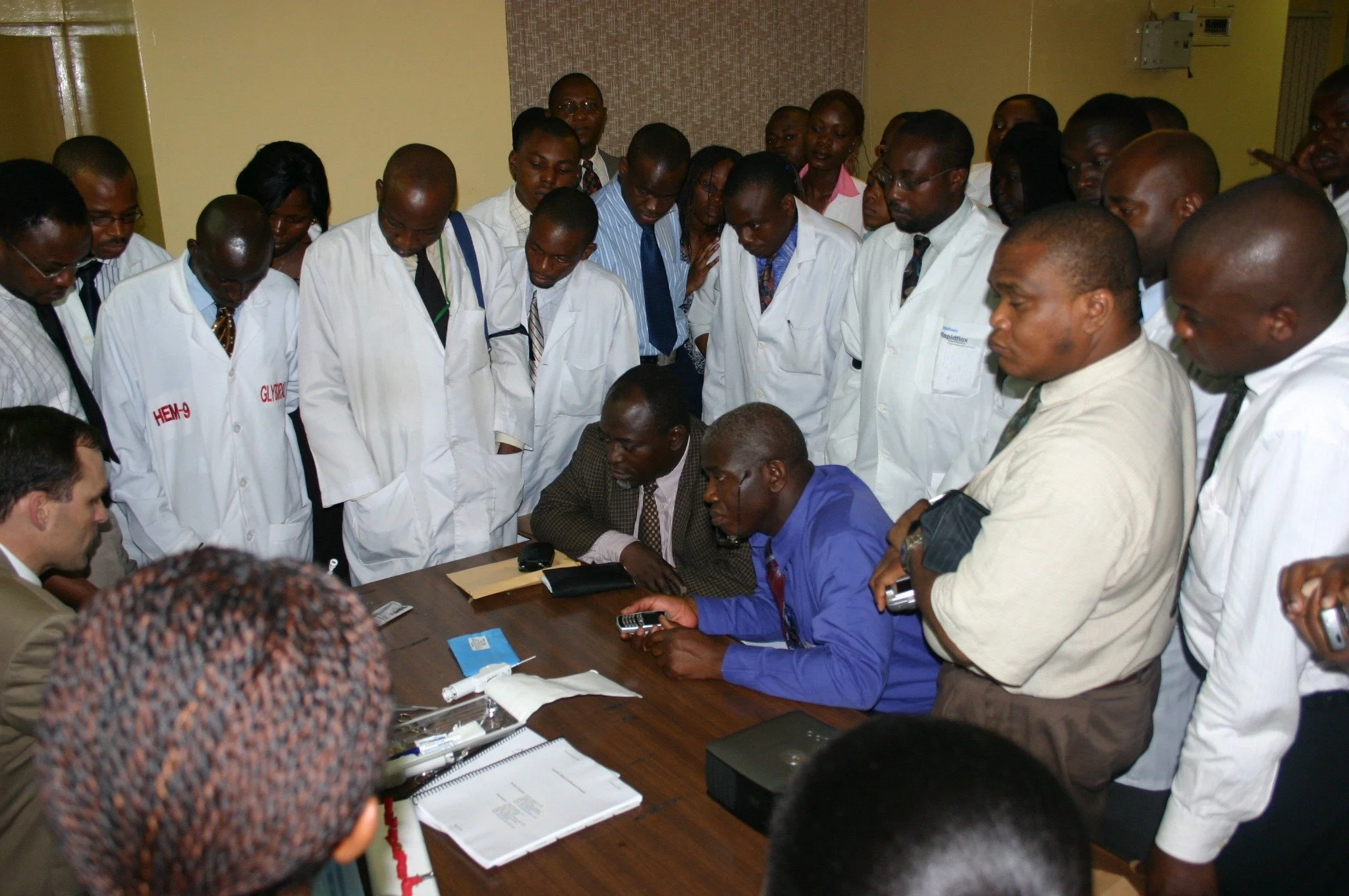 A group of doctors in white coats, gathered around a seated person