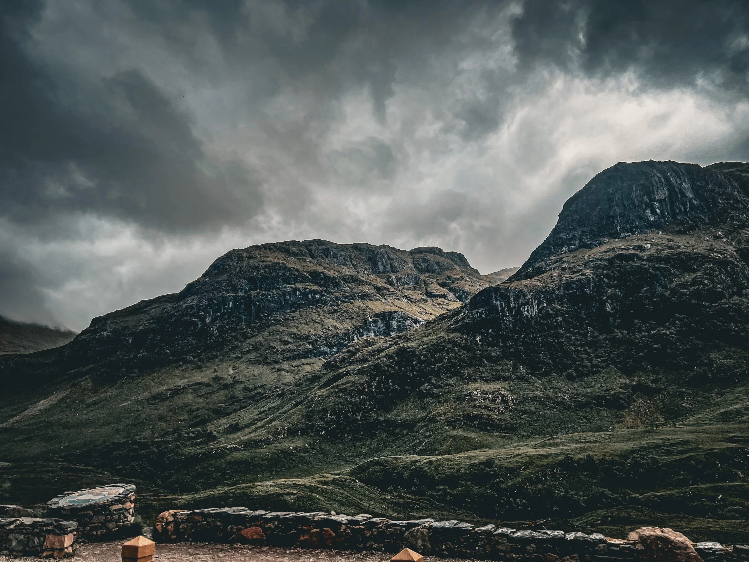 Mountains with dark, cloudy sky and rocky foreground.