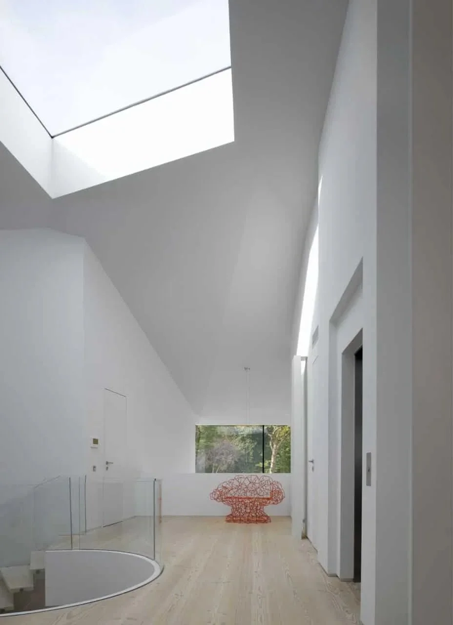 View of the first-floor landing of the minimalist house with white walls, Dinesen wooden floor,  glass staircase by Santambrogio Milano. Sheldon Avenue House, Hampstead.
