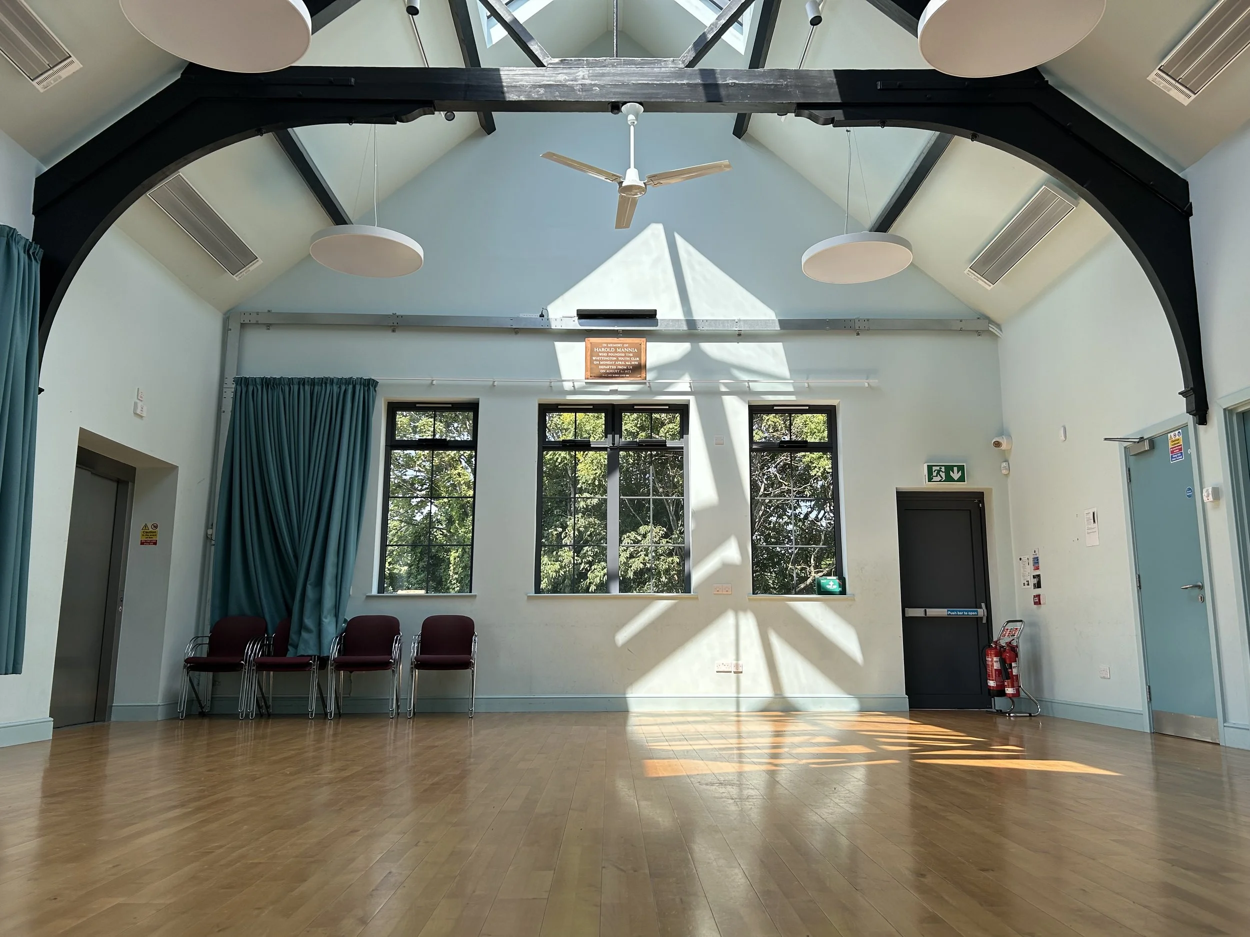 Top floor music and event room with wooden floor, black beams and large windows and skylight. Whittington Park Community Centre