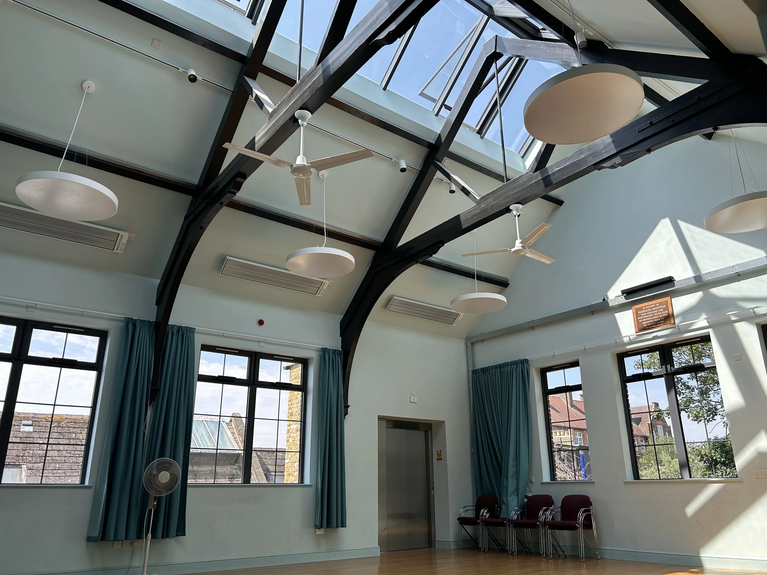 Top floor music and event room with wooden floor, black beams and large windows and skylight. Whittington Park Community Centre