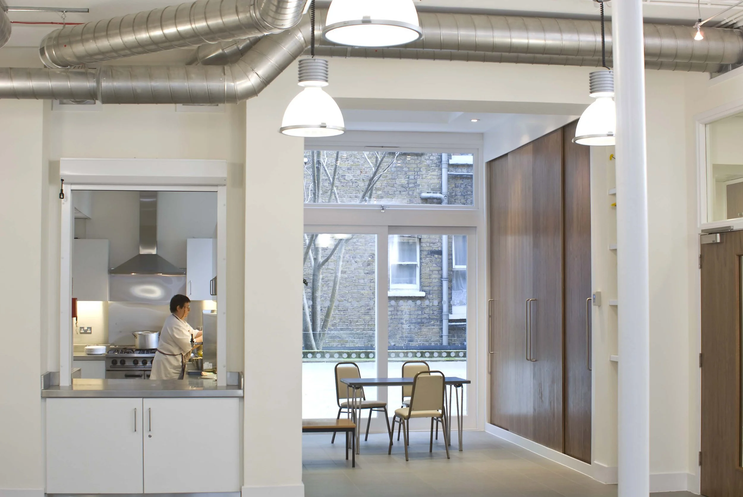View of the Modern kitchen with a chef cooking, large windows at the rear of the ground floor. Marchmont Community Centre
