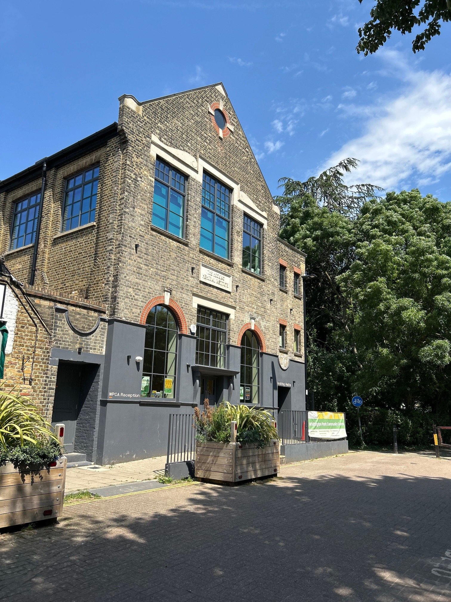 Front façade of the Hocking Halls building in brickwork with large windows and a small clock on the upper part. Whittington Park Community Centre