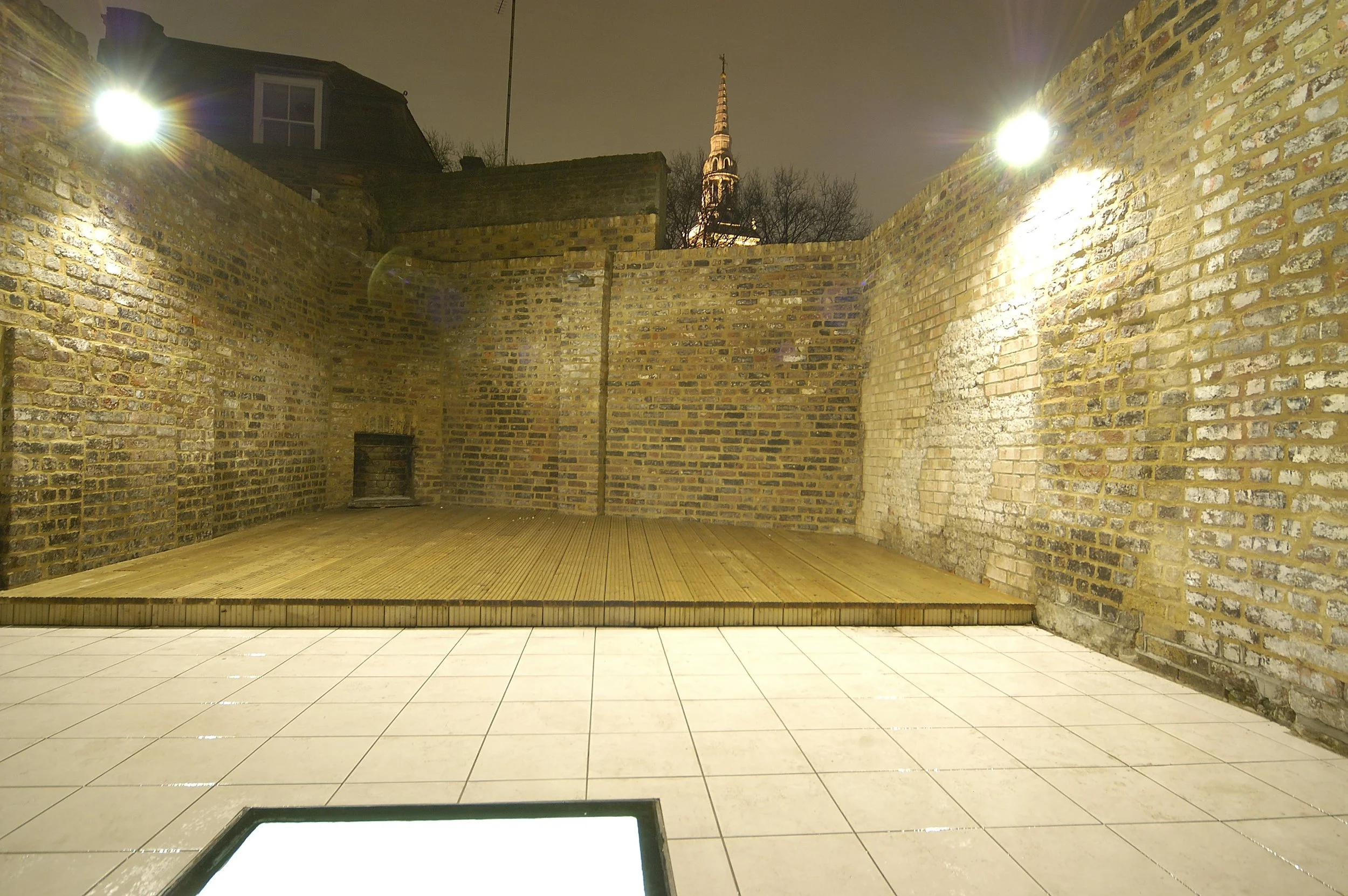 Brick inner courtyard with decking area and skylight for the basement room in the Cross Street renovate Grade II Listed House