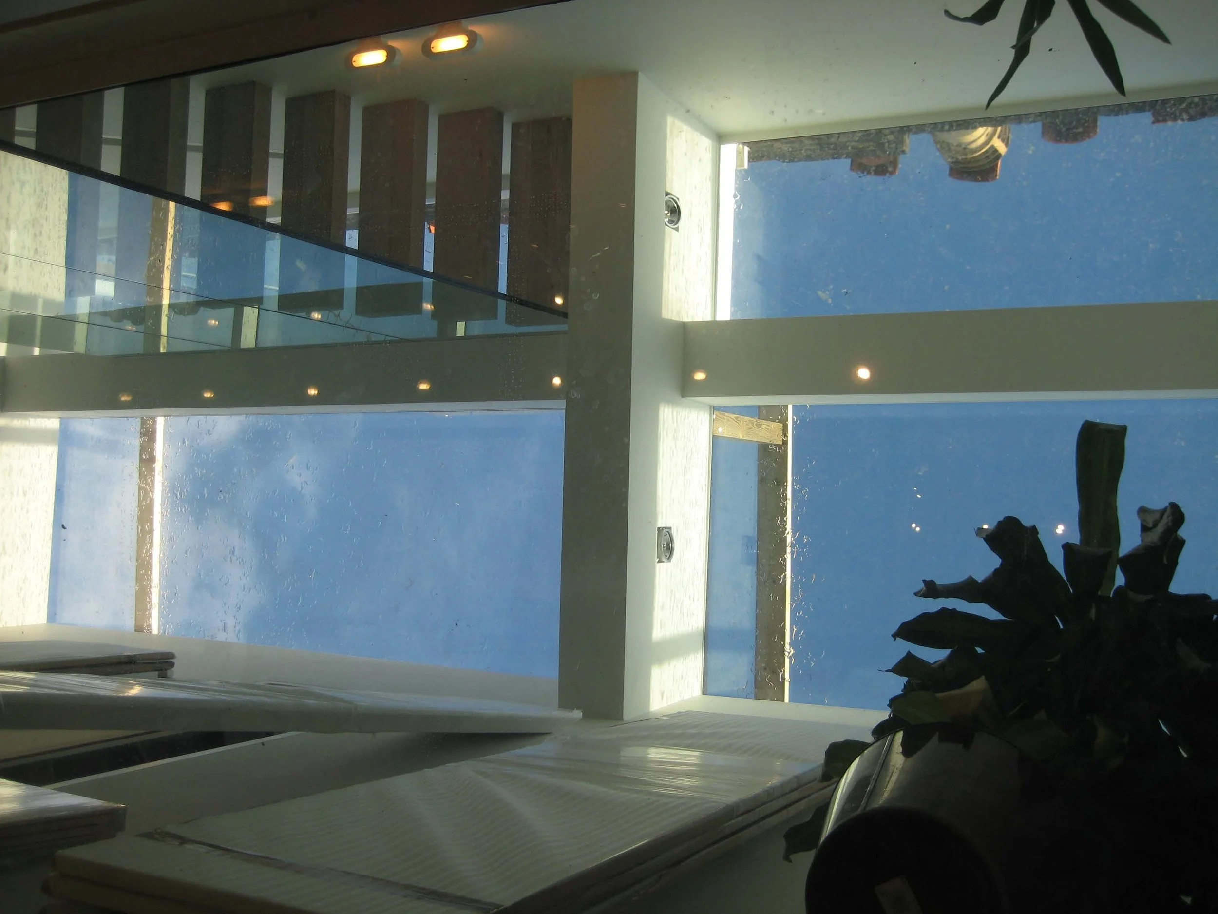 Interior view of a modern large skylight provide access to the large roof terrace showing a cityscape with tall buildings and a blue sky. South Kensington House