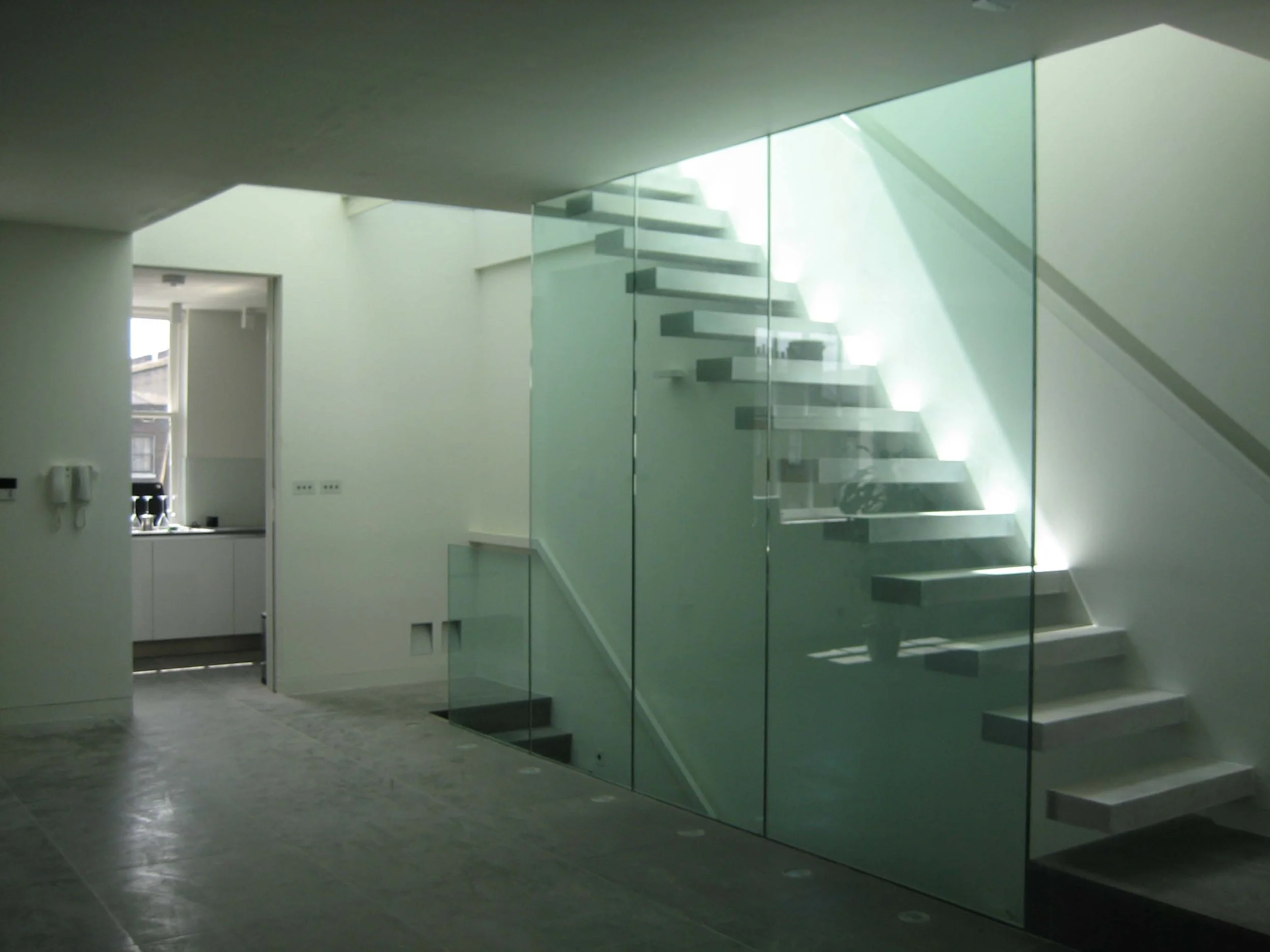 View of modern floating staircase enclosed in glass from the third floor to the fourth and to the roof terrace accessible by an electrical skylight. South Kensington House