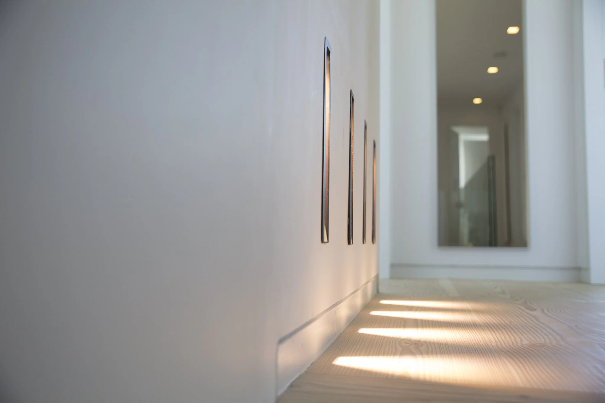 First floor landing with Dinesen timber floor, white wall and wall recessed Viabizzuno lights. Sutherland Avenue House
