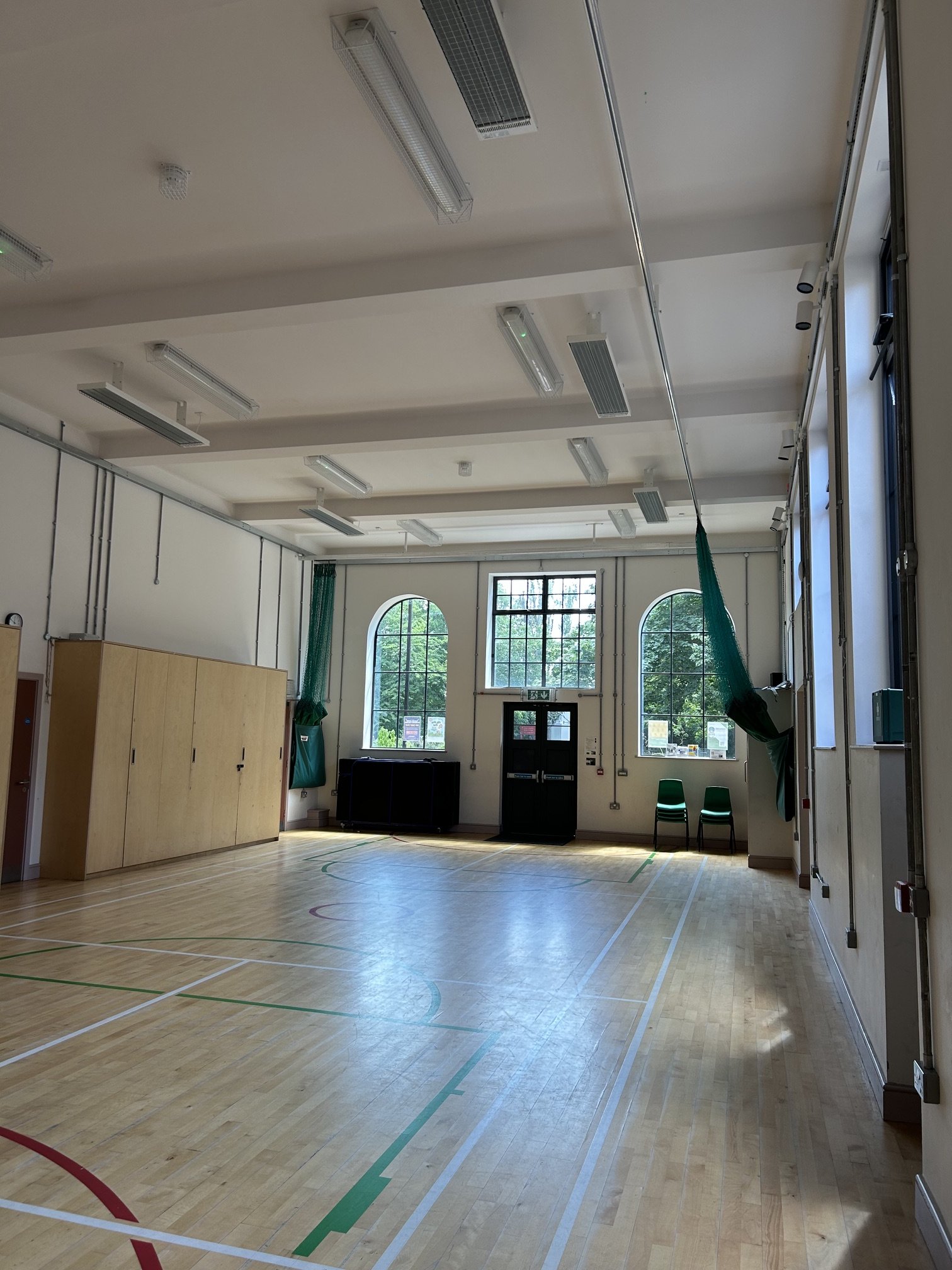 Ground floor indoor gymnasium and multi-purpose room with wooden floors, high windows, and storage cabinets along the sides.  Whittington Park Community Centre