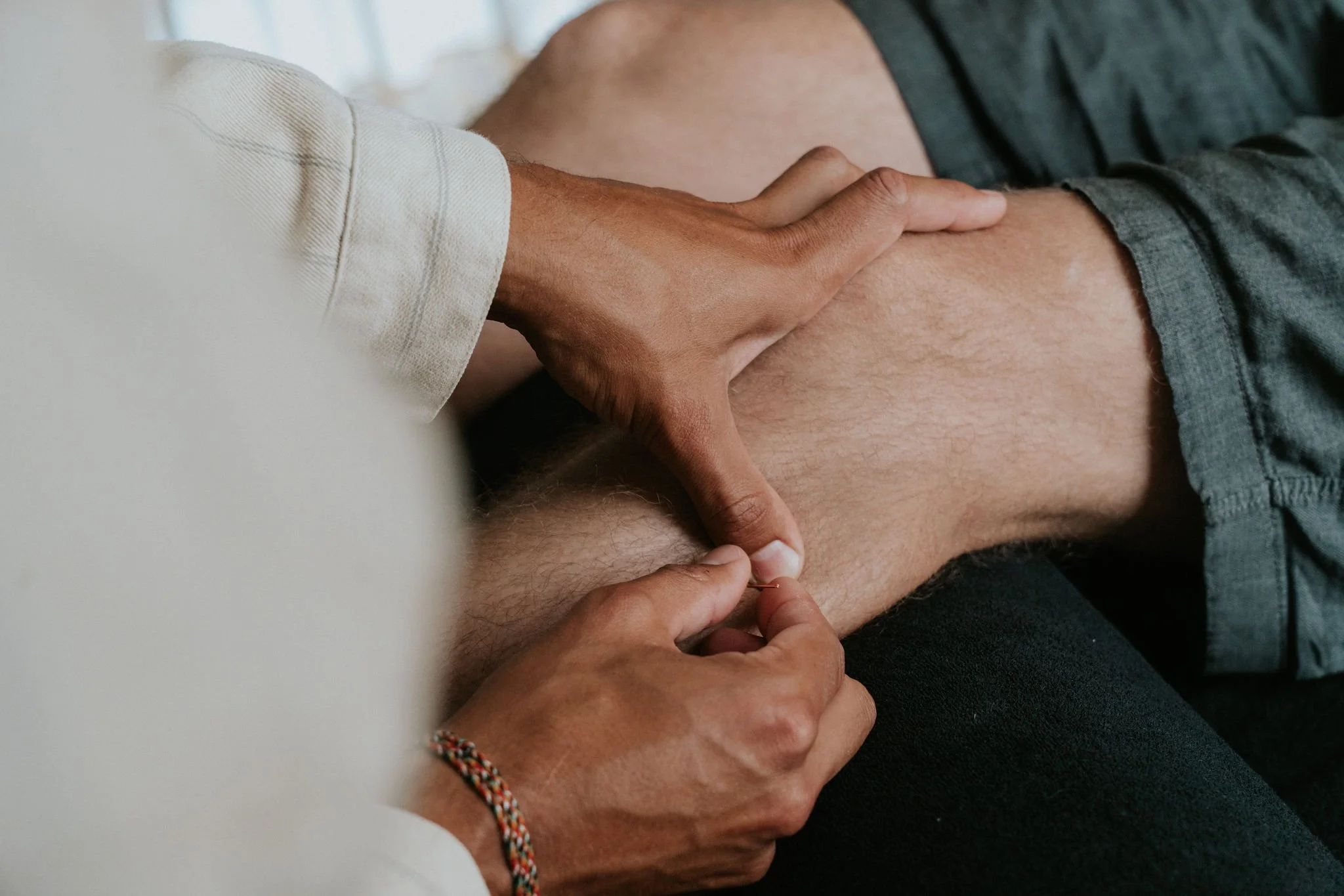Man die een acupunctuursessie krijgt, waarbij een acupunctuurnaal wordt ingebracht in het been.