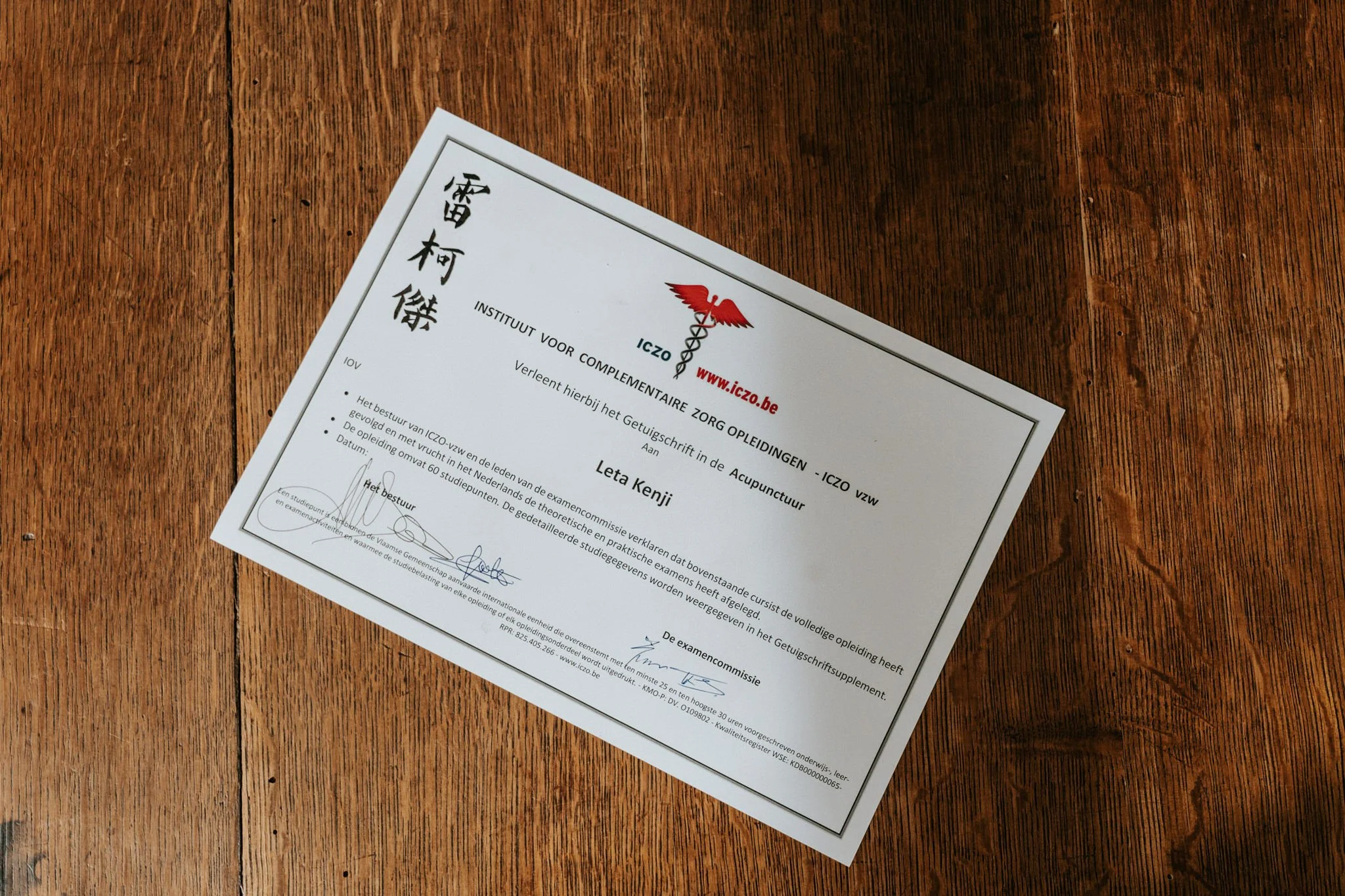 Diploma can acupunctuur op een houten tafel.